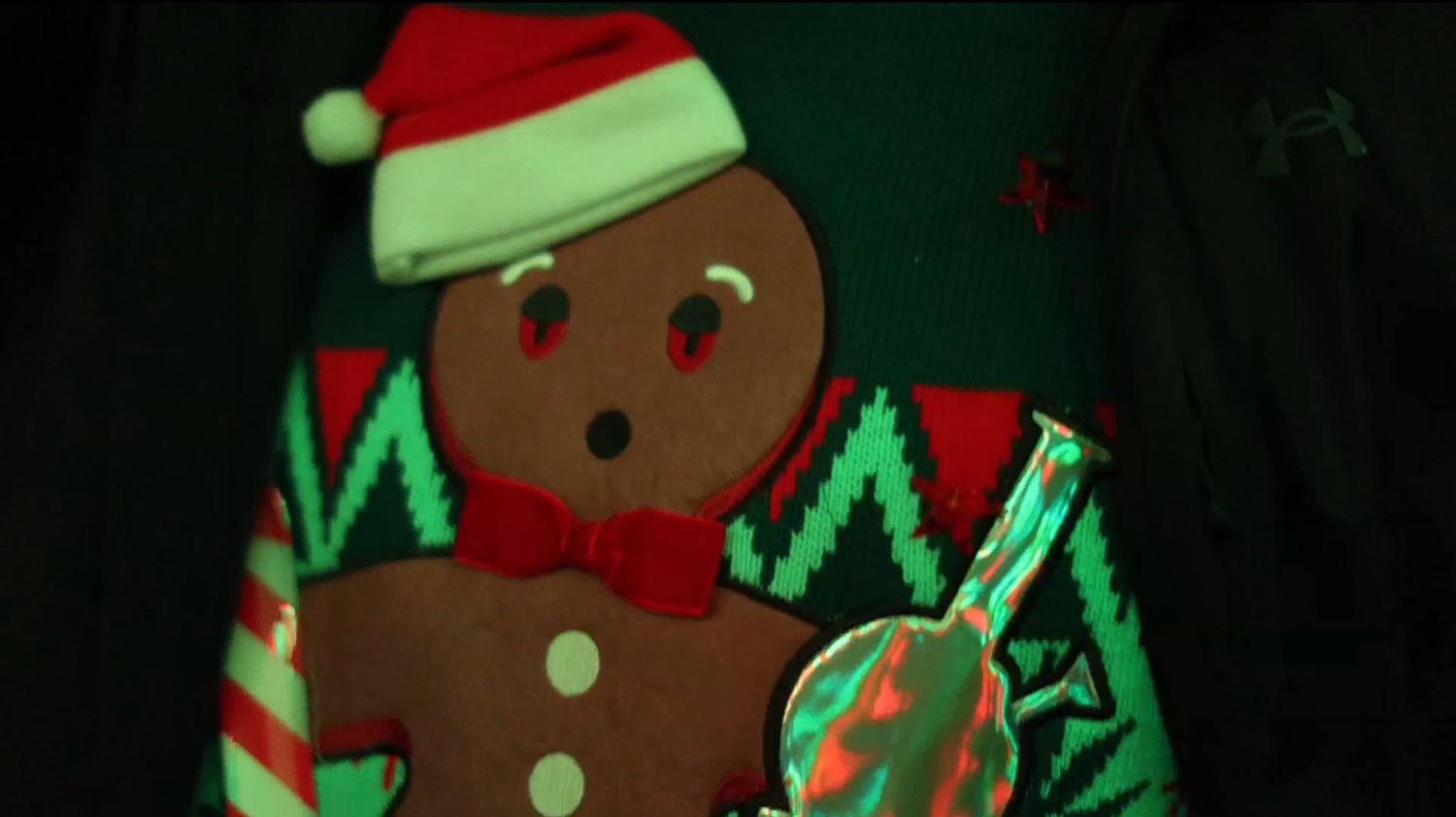 Decorative gingerbread man ornament with festive holiday attire against dark background.