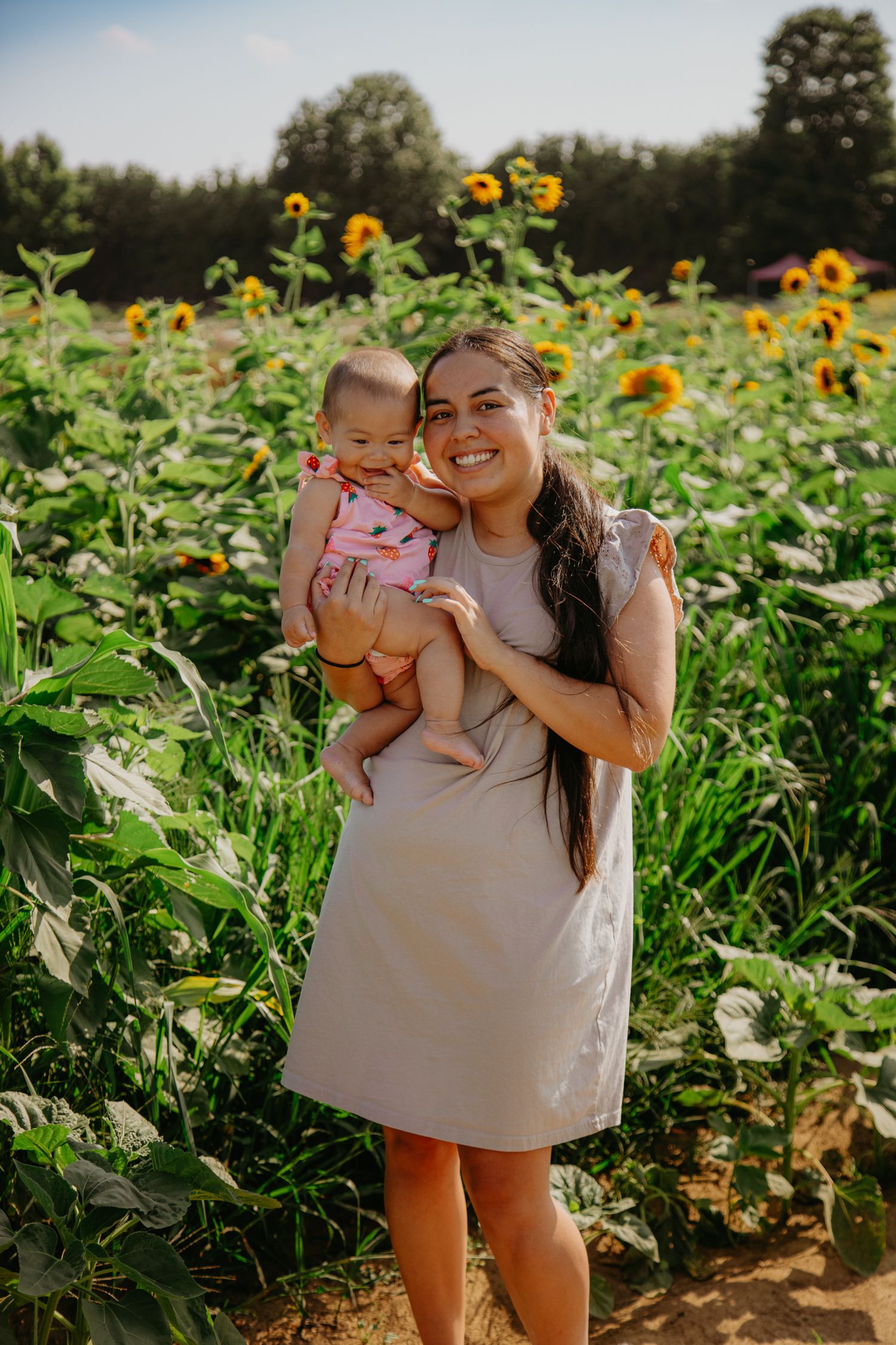 Mother and child portrait in a sunflower field during golden hour.