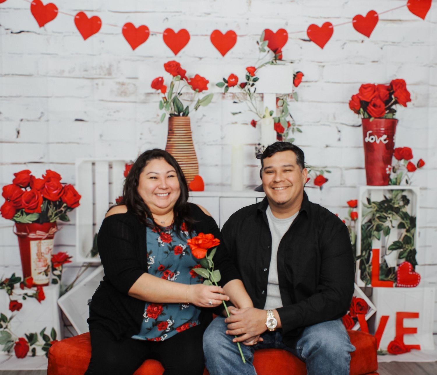 Family laughing together during Valentine's themed photo shoot with red hearts.