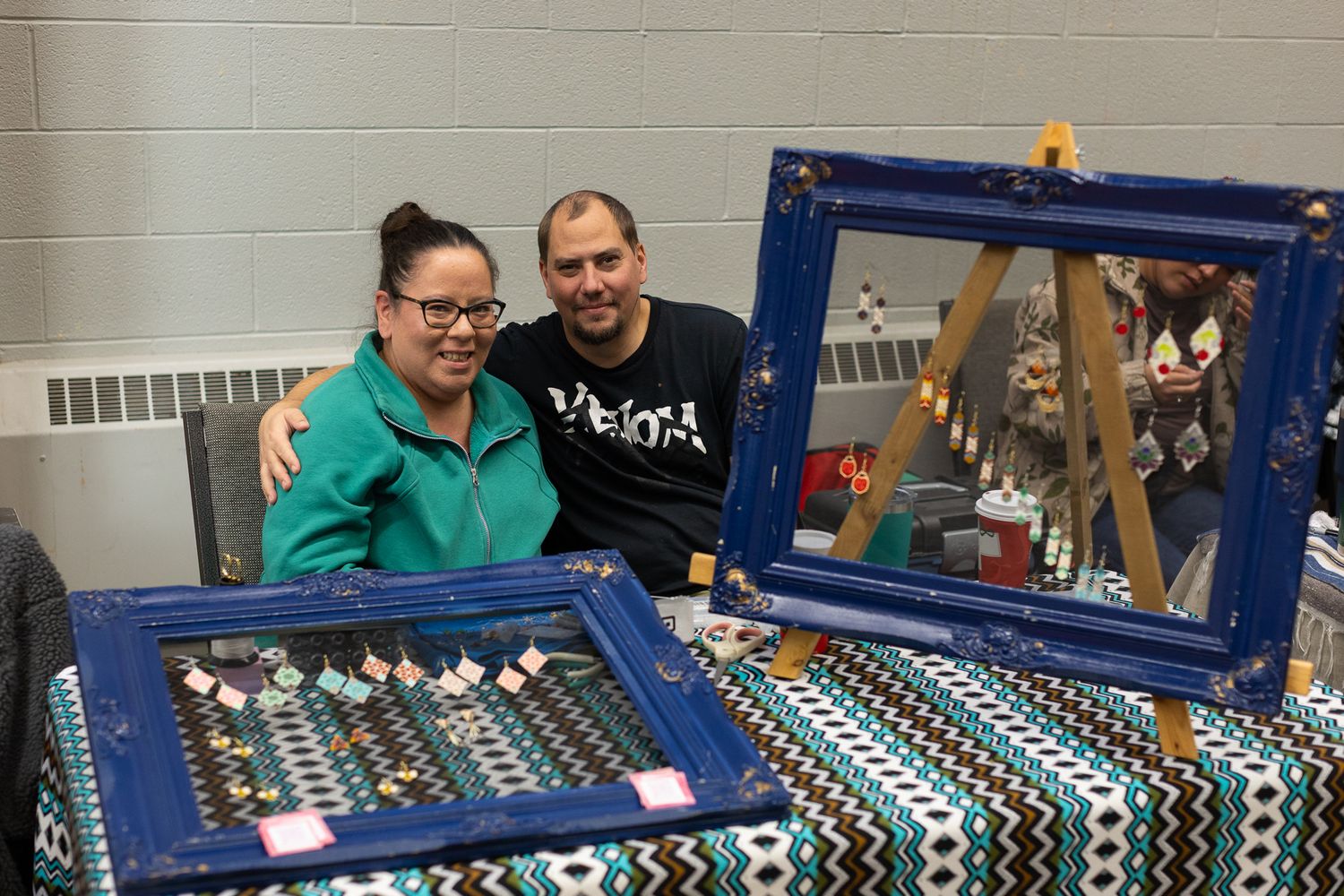 Vendors selling crafts and merchandise at tables with blue display cases.