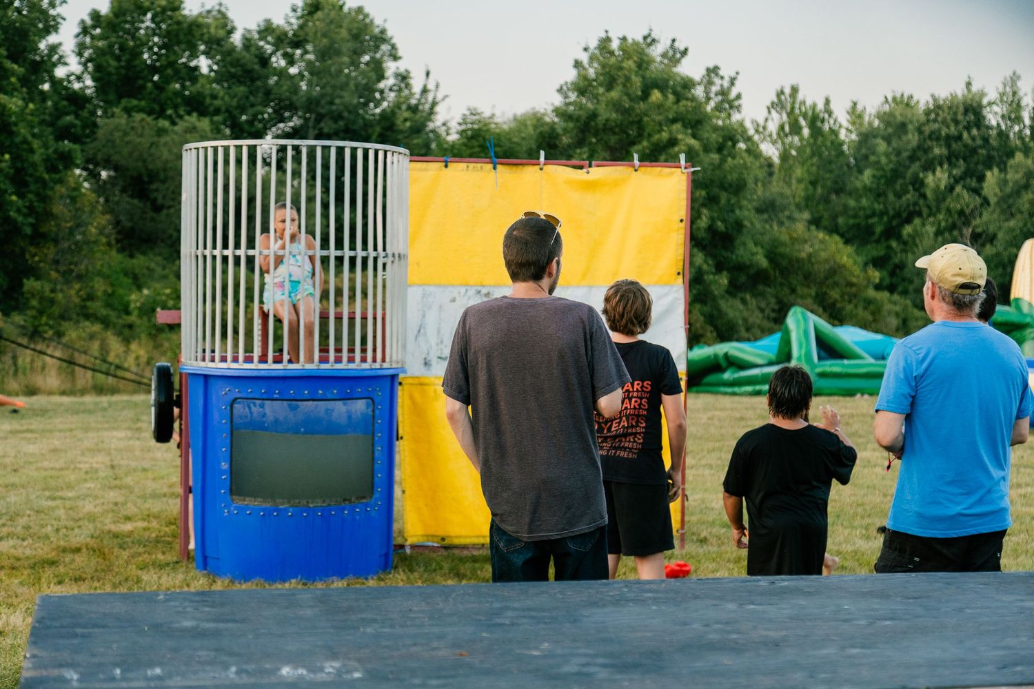 People watching someone in a dunk tank attraction at an outdoor carnival.
