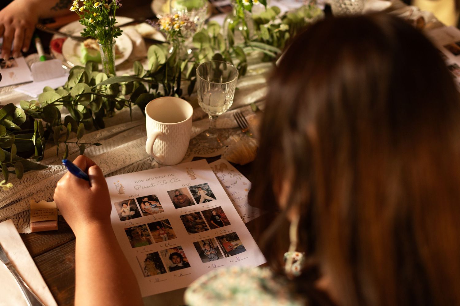 Someone looking through a photo album at a table decorated with greenery and flowers.