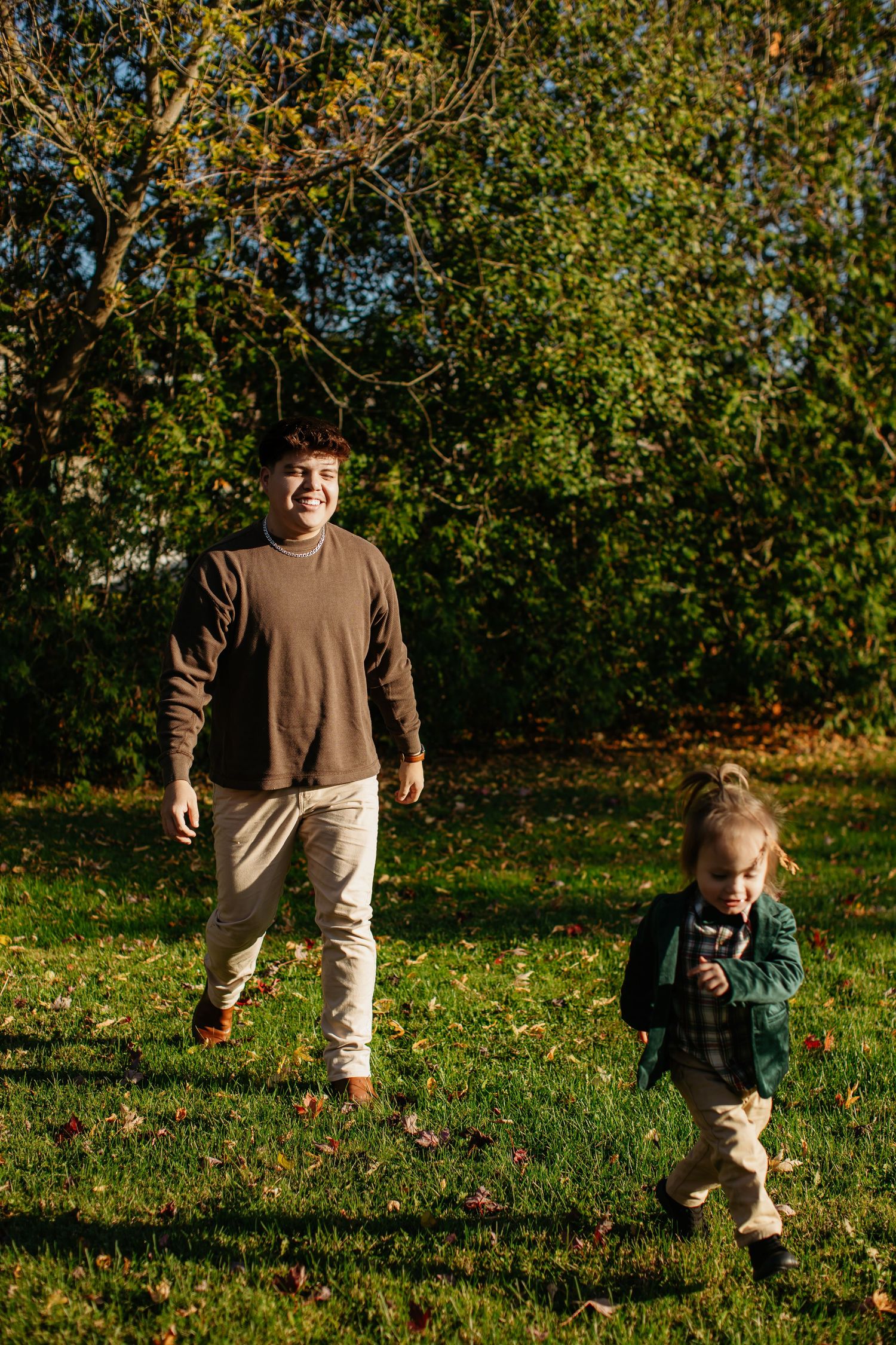 People enjoying a sunny autumn day on grass beneath trees with golden leaves.