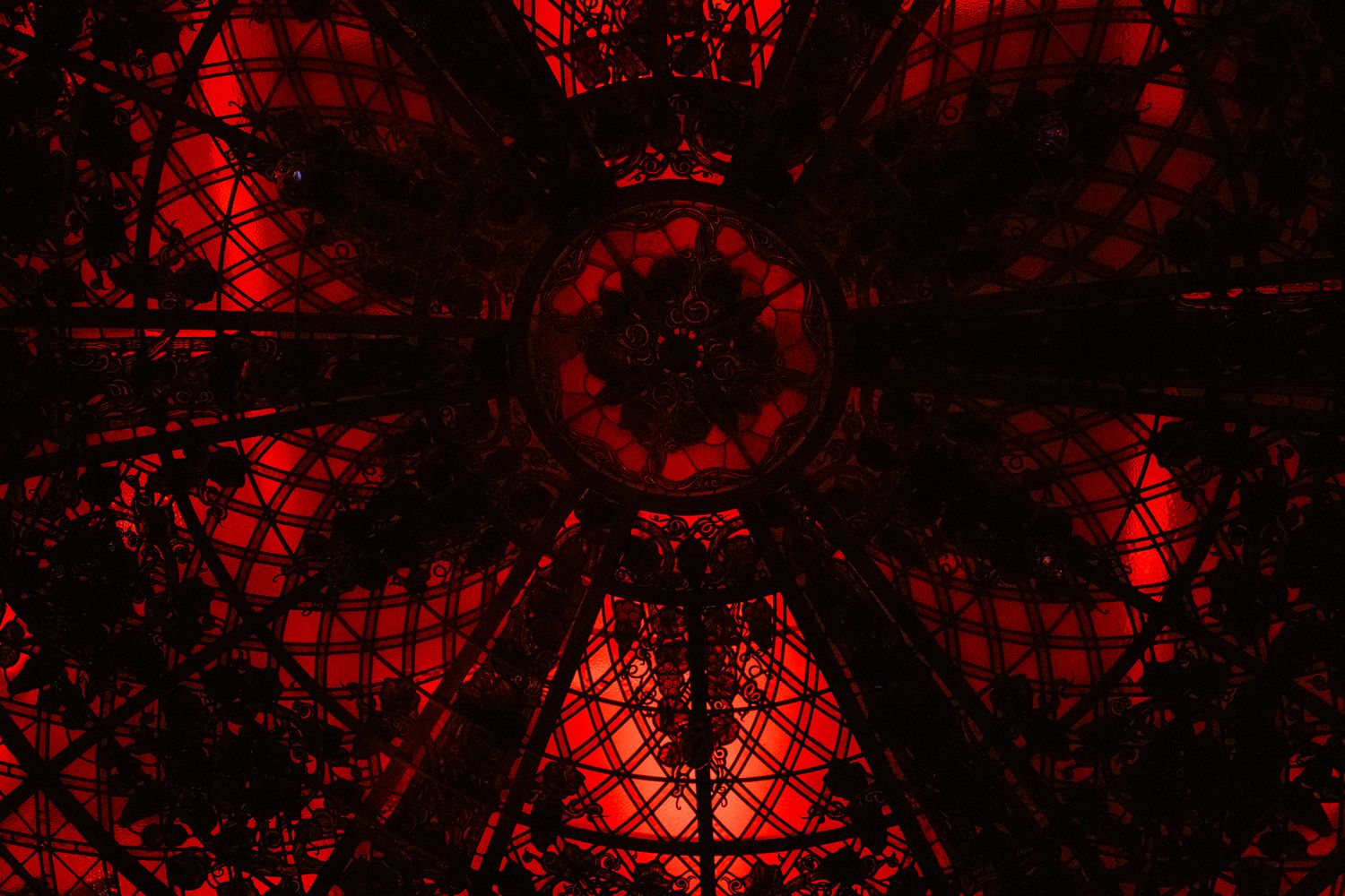 Abstract red geometric pattern of illuminated ceiling structure creating a symmetrical design.