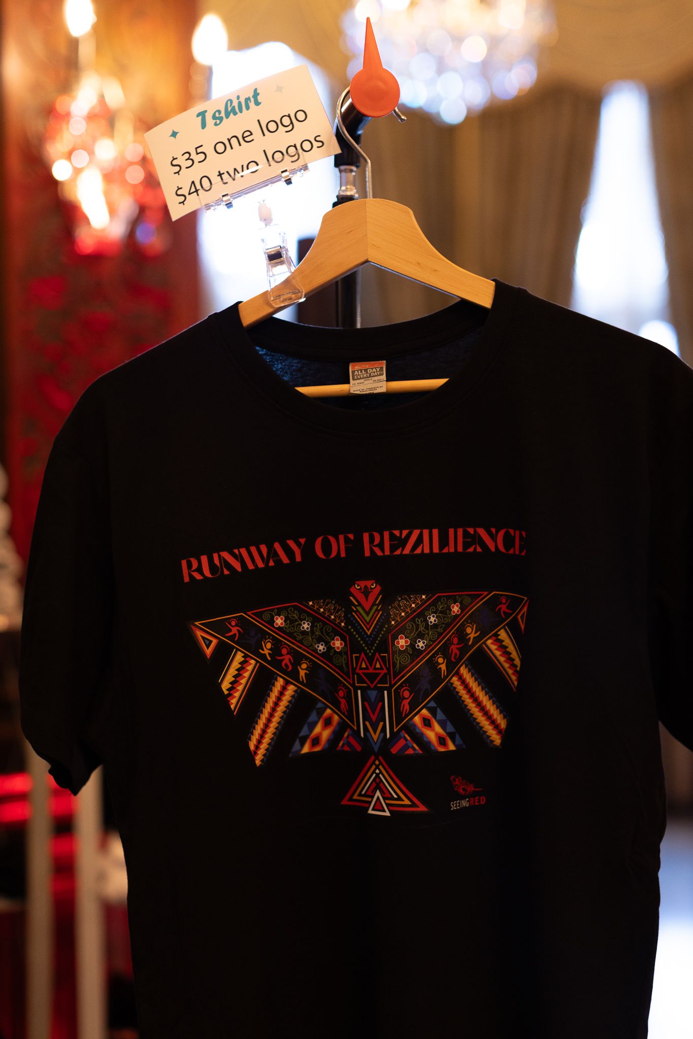 Black Runway of Rezilience t-shirt with Native thunderbird design on a hanger.