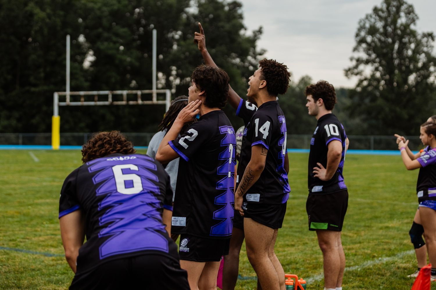 Rugby team players celebrate a score on the field during an outdoor tournament game.
