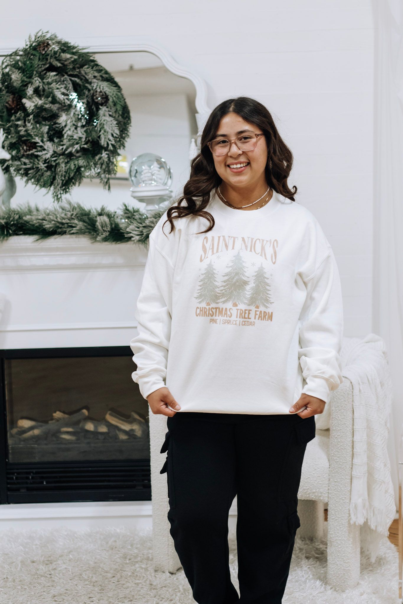 Holiday sweatshirts with Christmas tree farm designs displayed in bright white room.