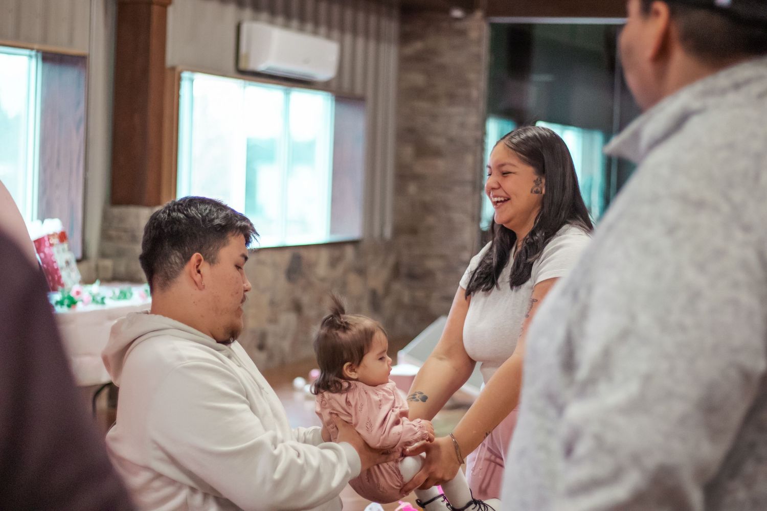 People gathered around tables at an indoor celebration event with natural lighting.