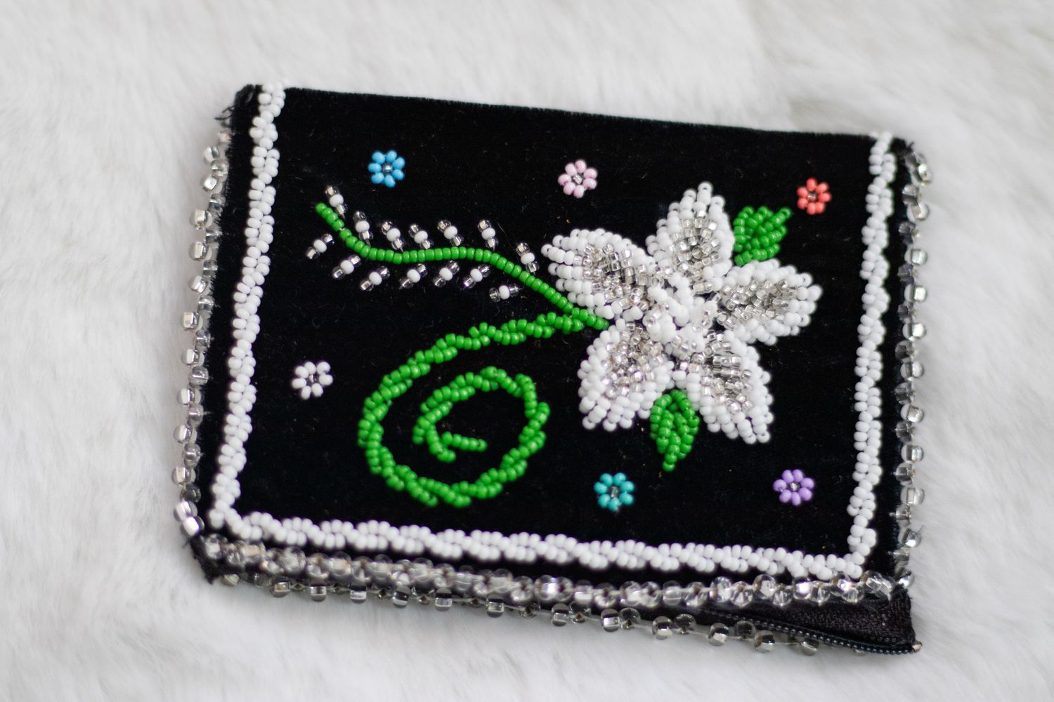 Beaded floral designs on black fabric with silver and green embellishments.