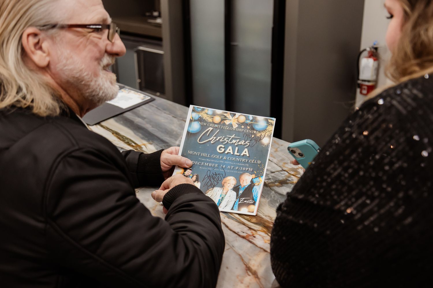 Attendees at a holiday event browse through books at a decorated table.
