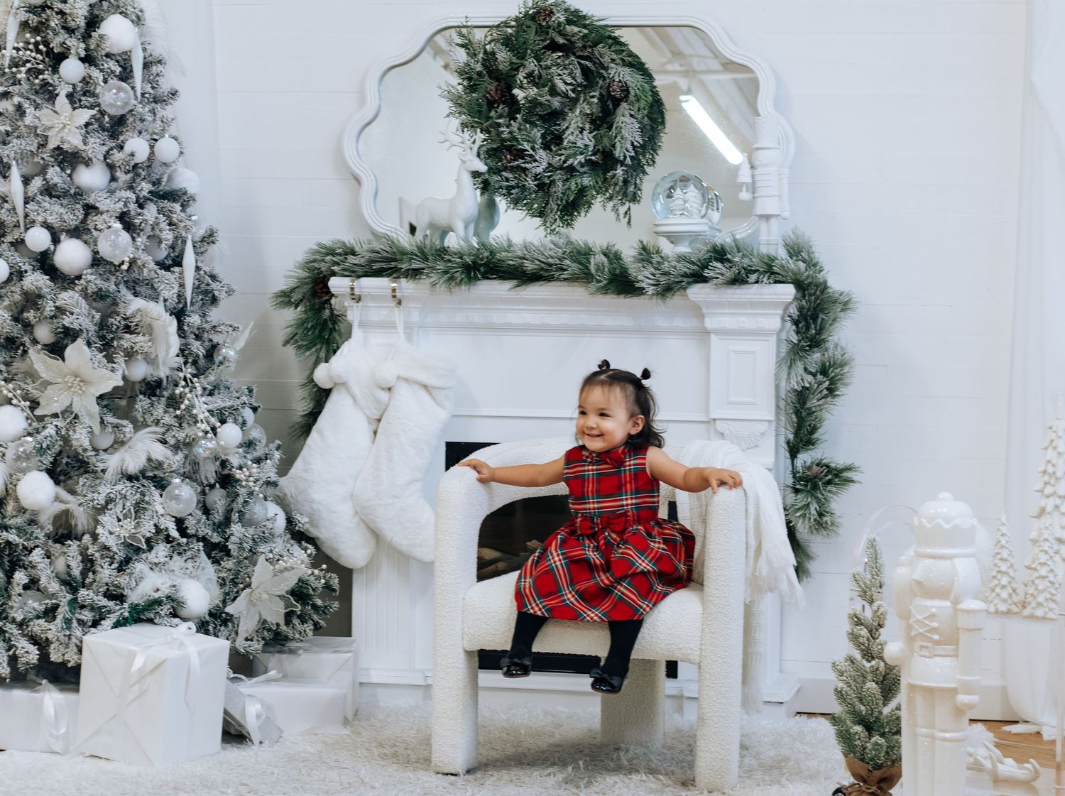 Holiday portraits by white flocked Christmas tree with decorative fireplace setting.