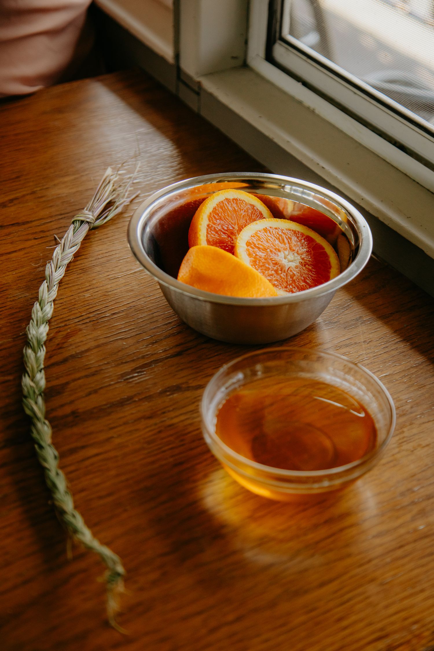 Fresh orange slices in a glass bowl on a wooden windowsill.