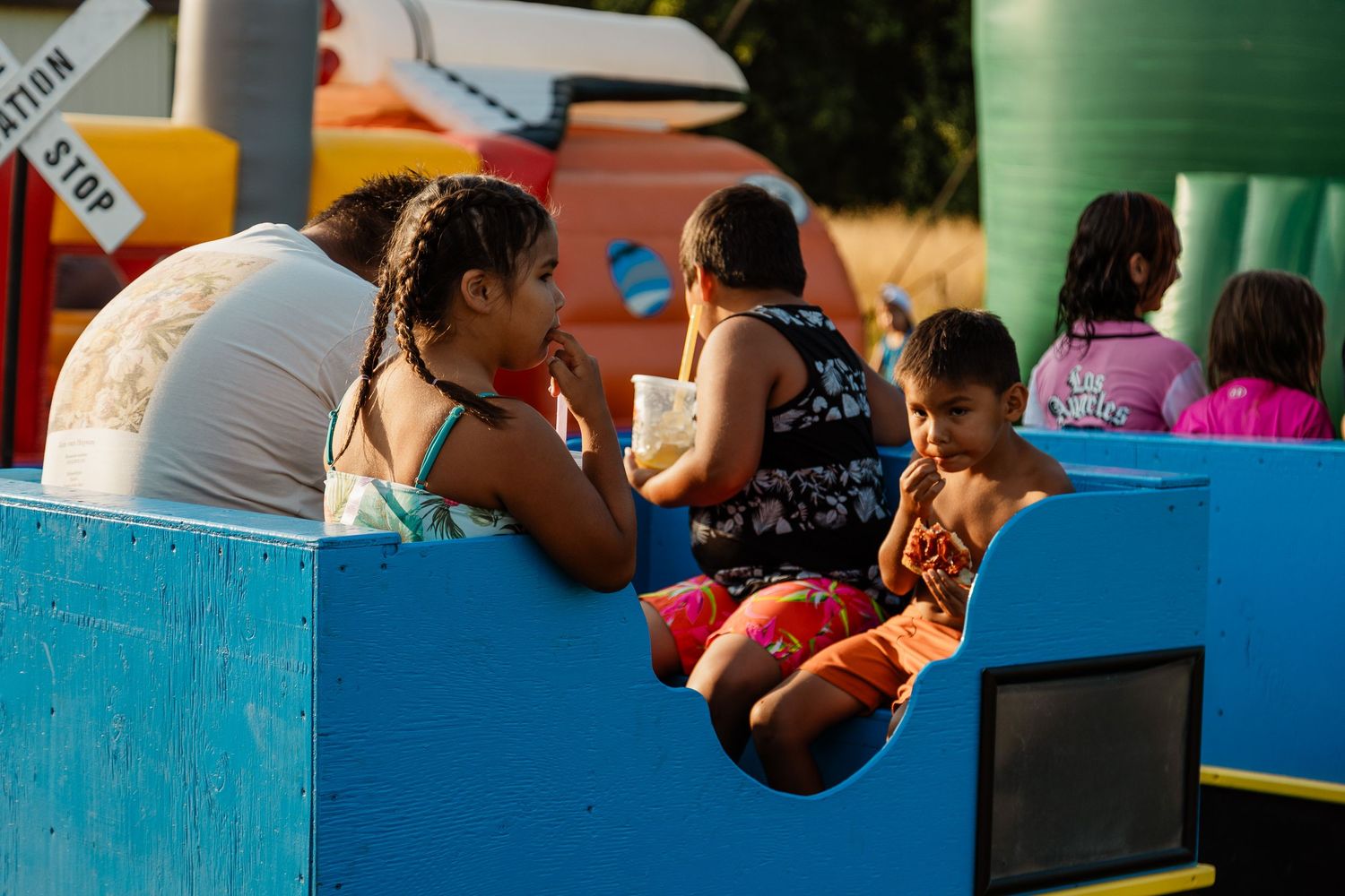 People relaxing in a blue play structure at an outdoor carnival.