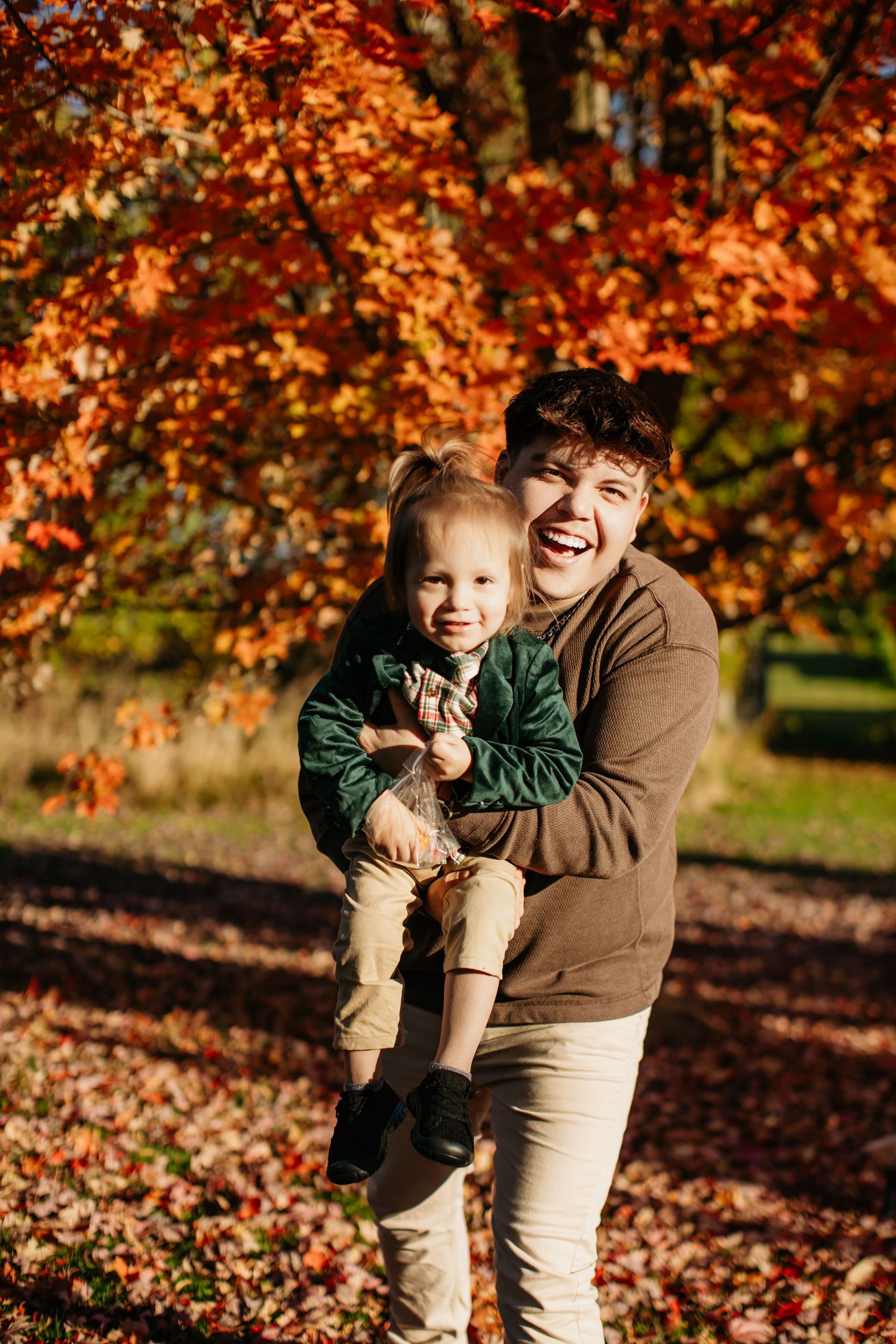 Joyful autumn portrait with vibrant orange fall foliage in the background.