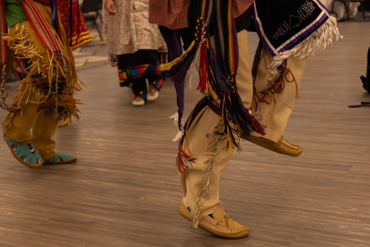 Traditional Native American regalia and moccasins visible during a cultural performance.
