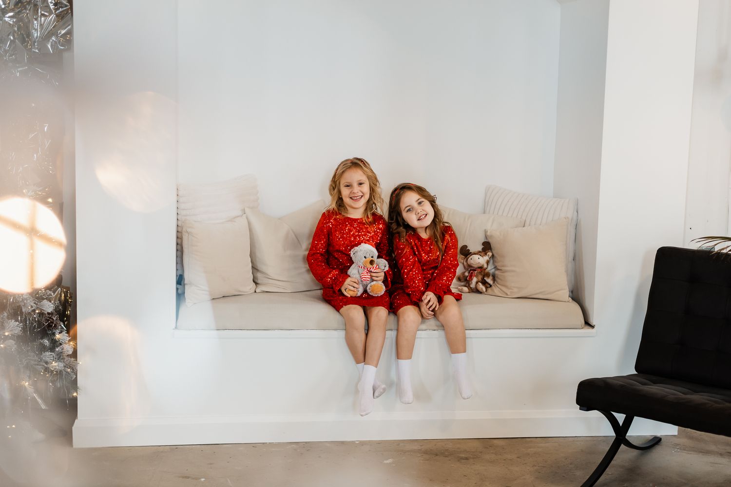 Playful indoor photoshoot with cozy winter sweaters on a white couch.