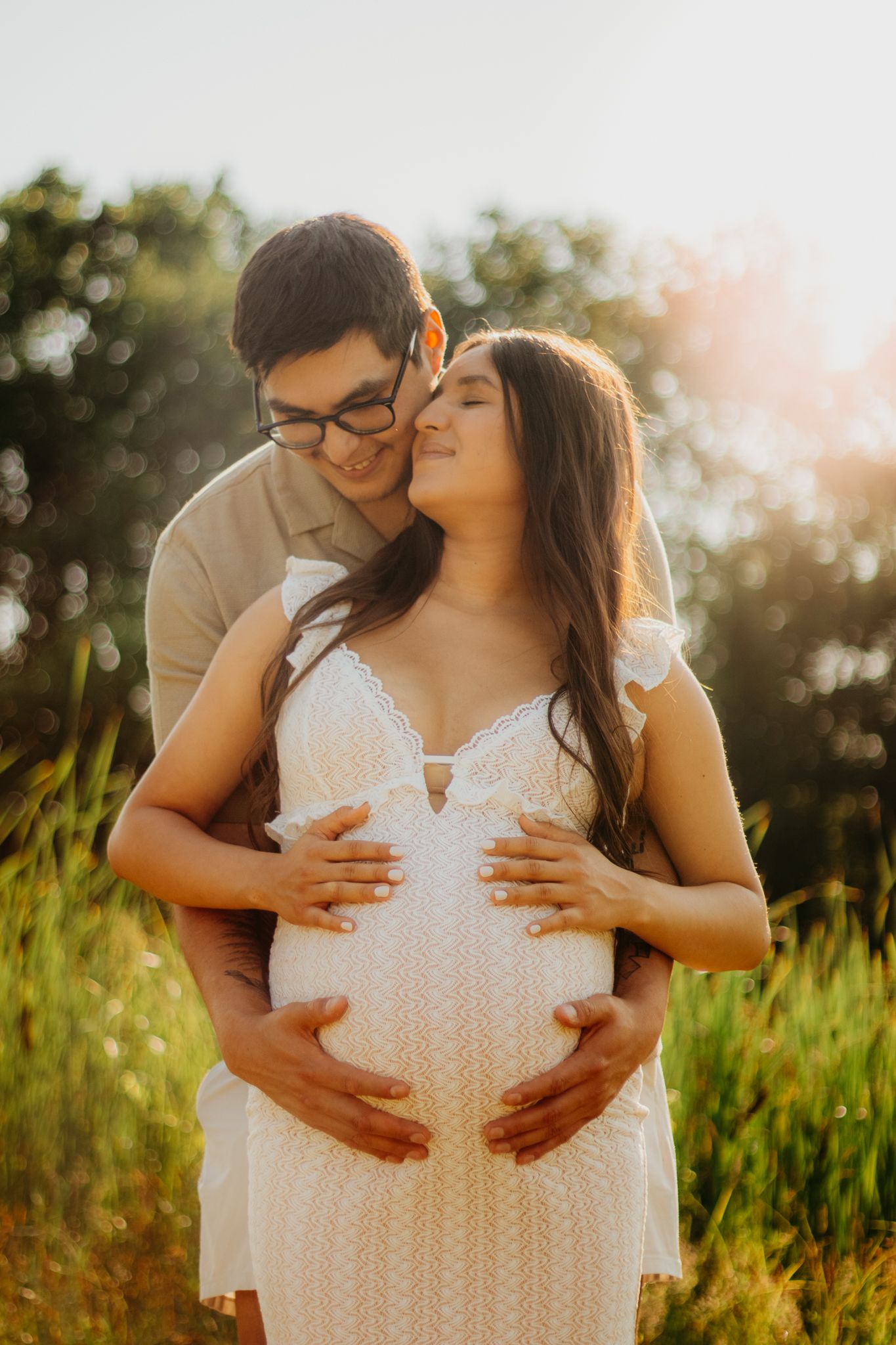 Intimate maternity photos at golden hour showing a couple sharing loving moments in nature.