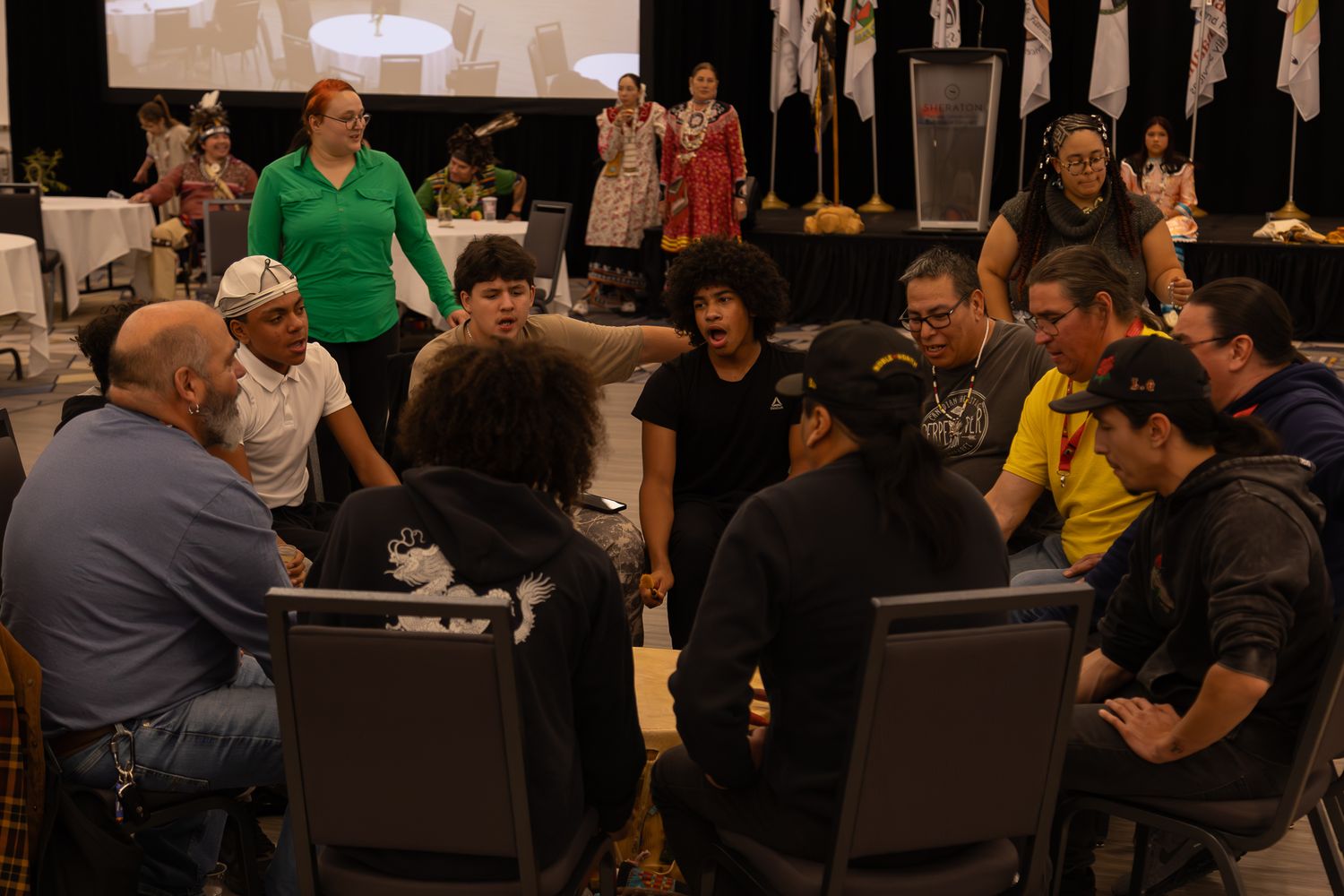 Attendees seated in rows of chairs during an indoor conference or meeting.