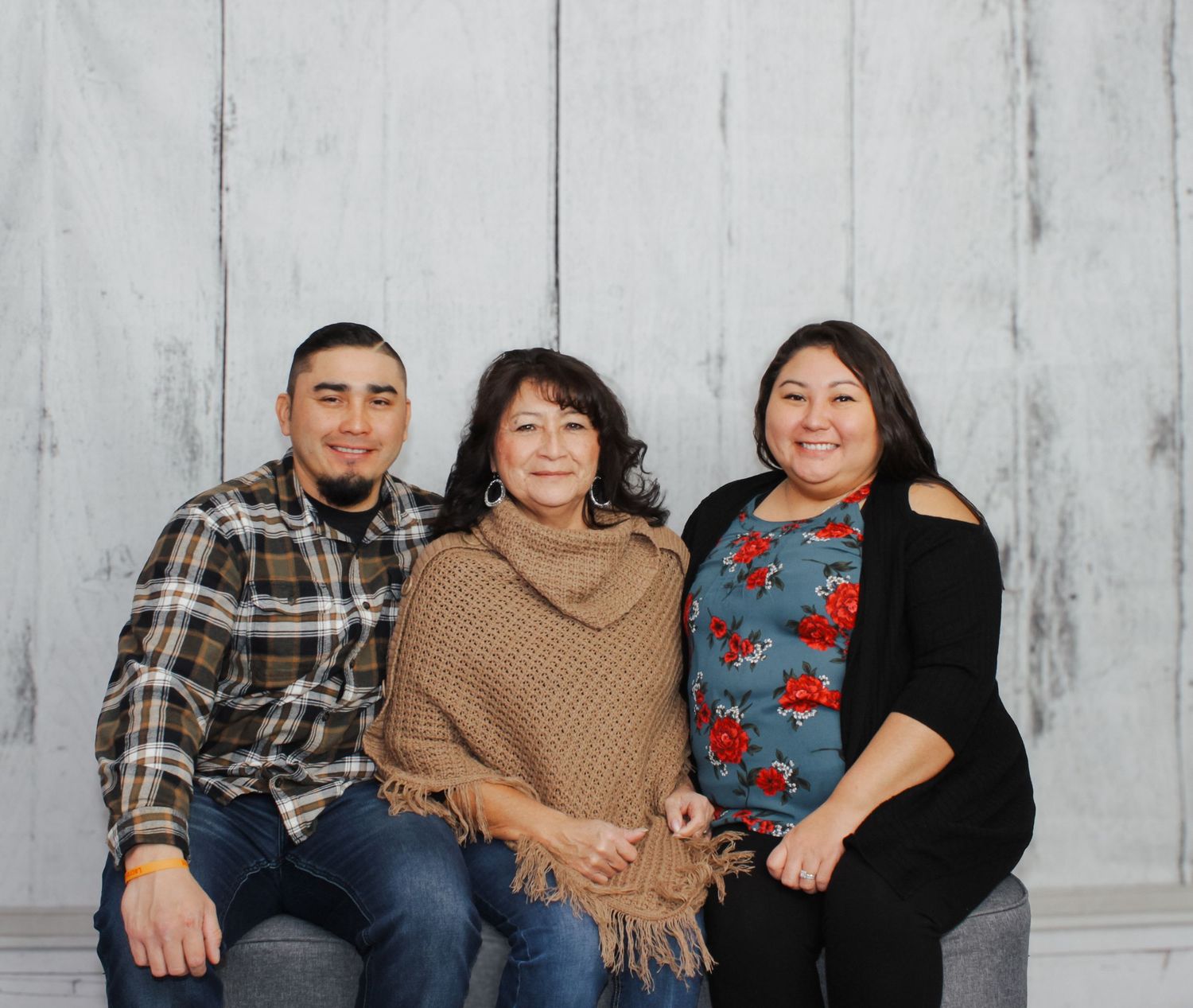 Family portrait of group sitting together on gray backdrop.
