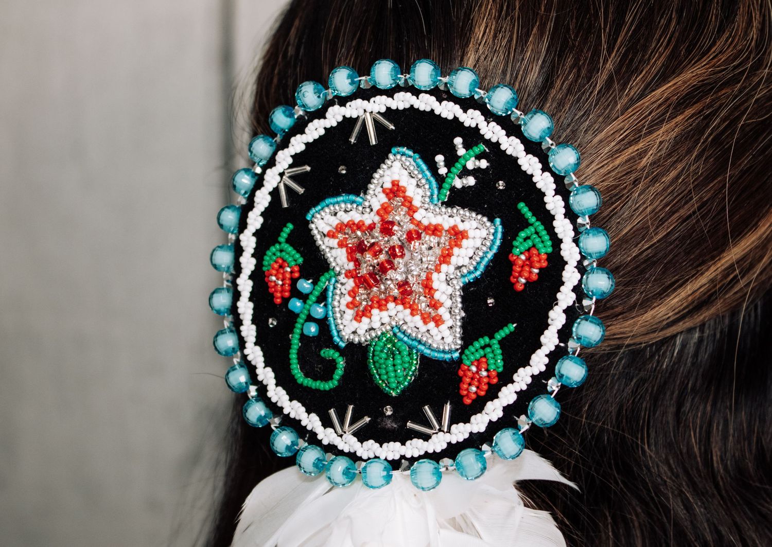 A detailed beadwork medallion featuring a red star pattern with turquoise beaded border.