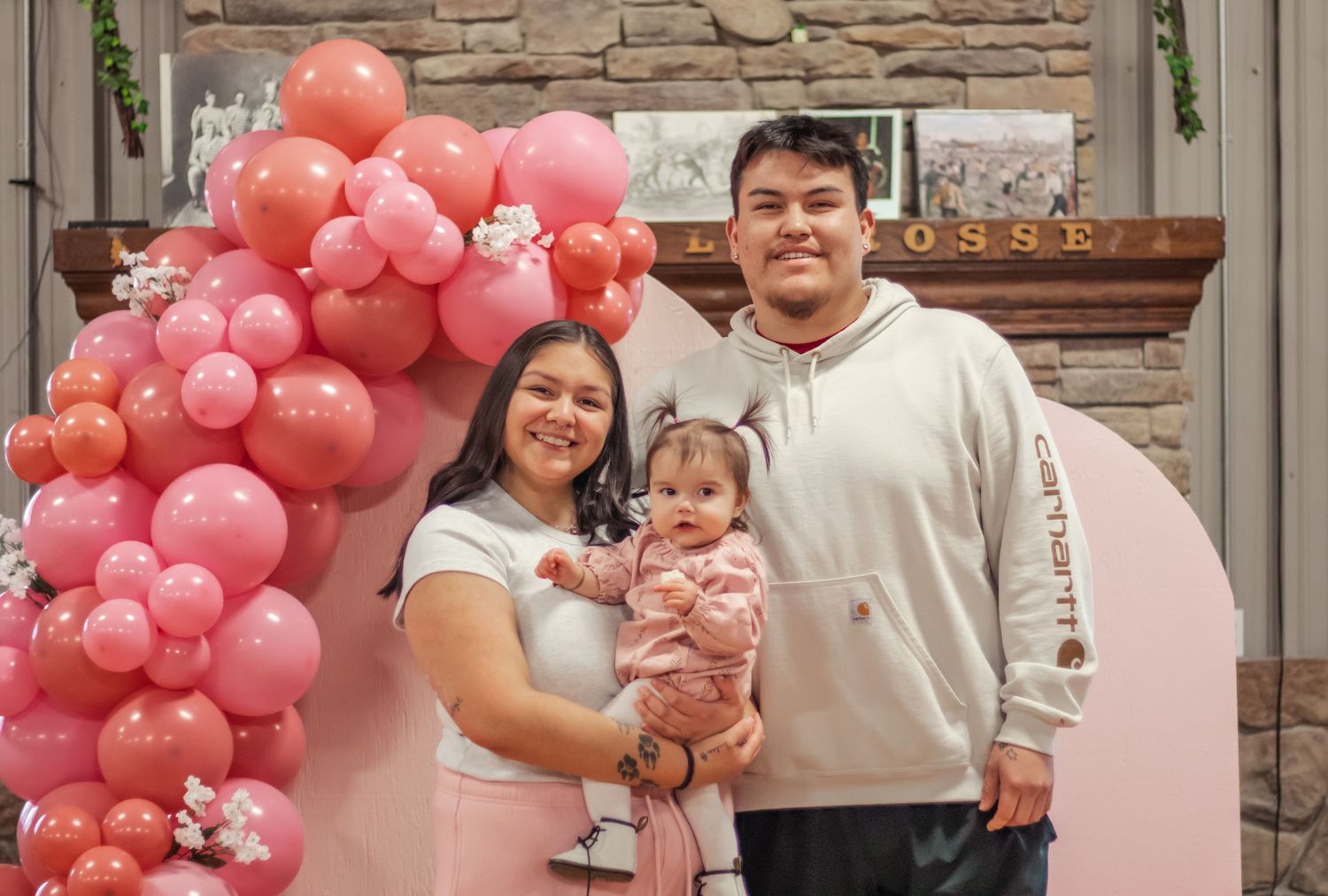 Pink balloon arch decorates a celebration space with stone wall accents.
