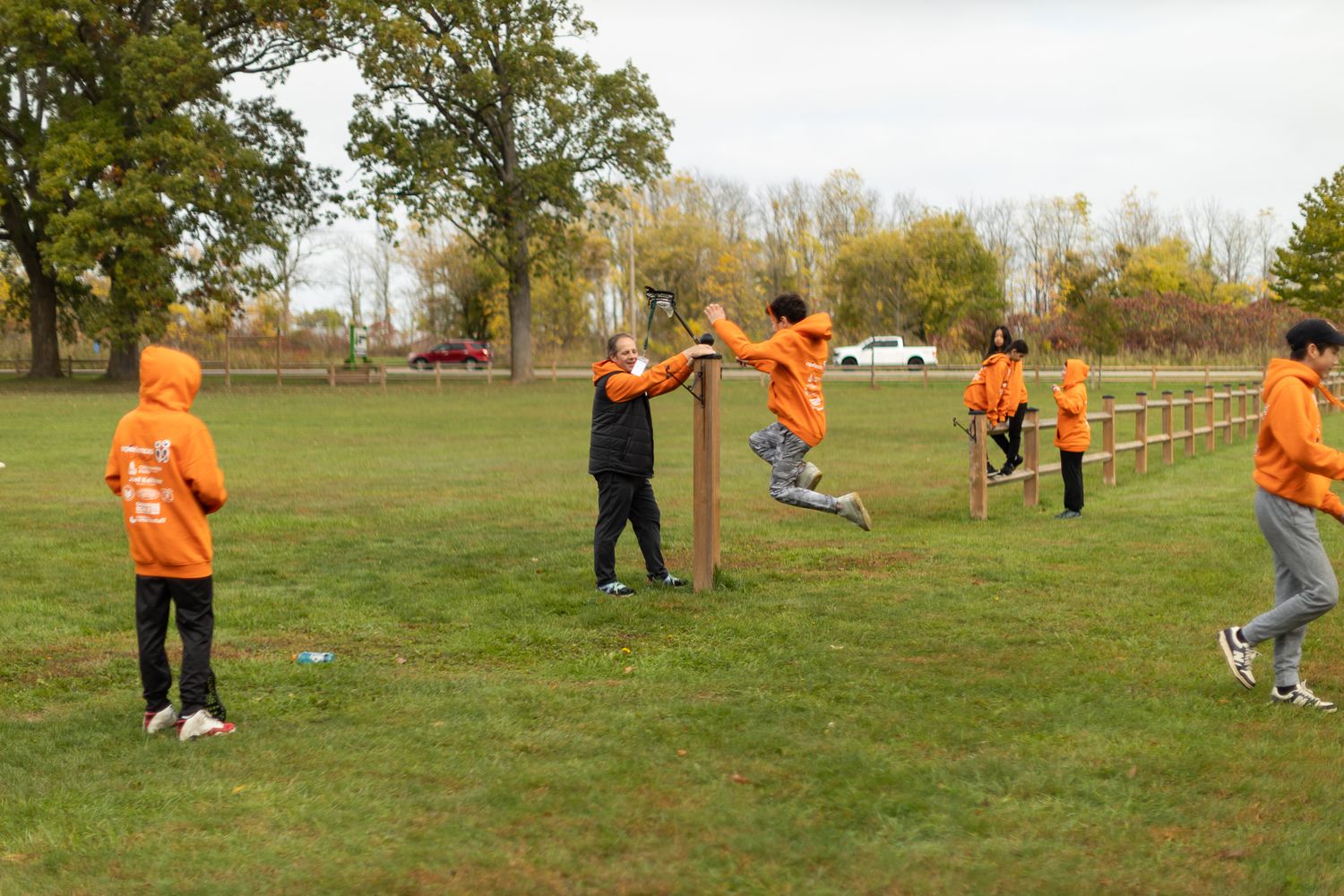People in orange shirts playing and gathering on a grassy field.