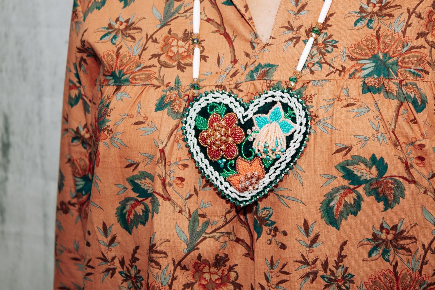 Peach-colored fabric with teal floral print and decorative beaded embellishments.