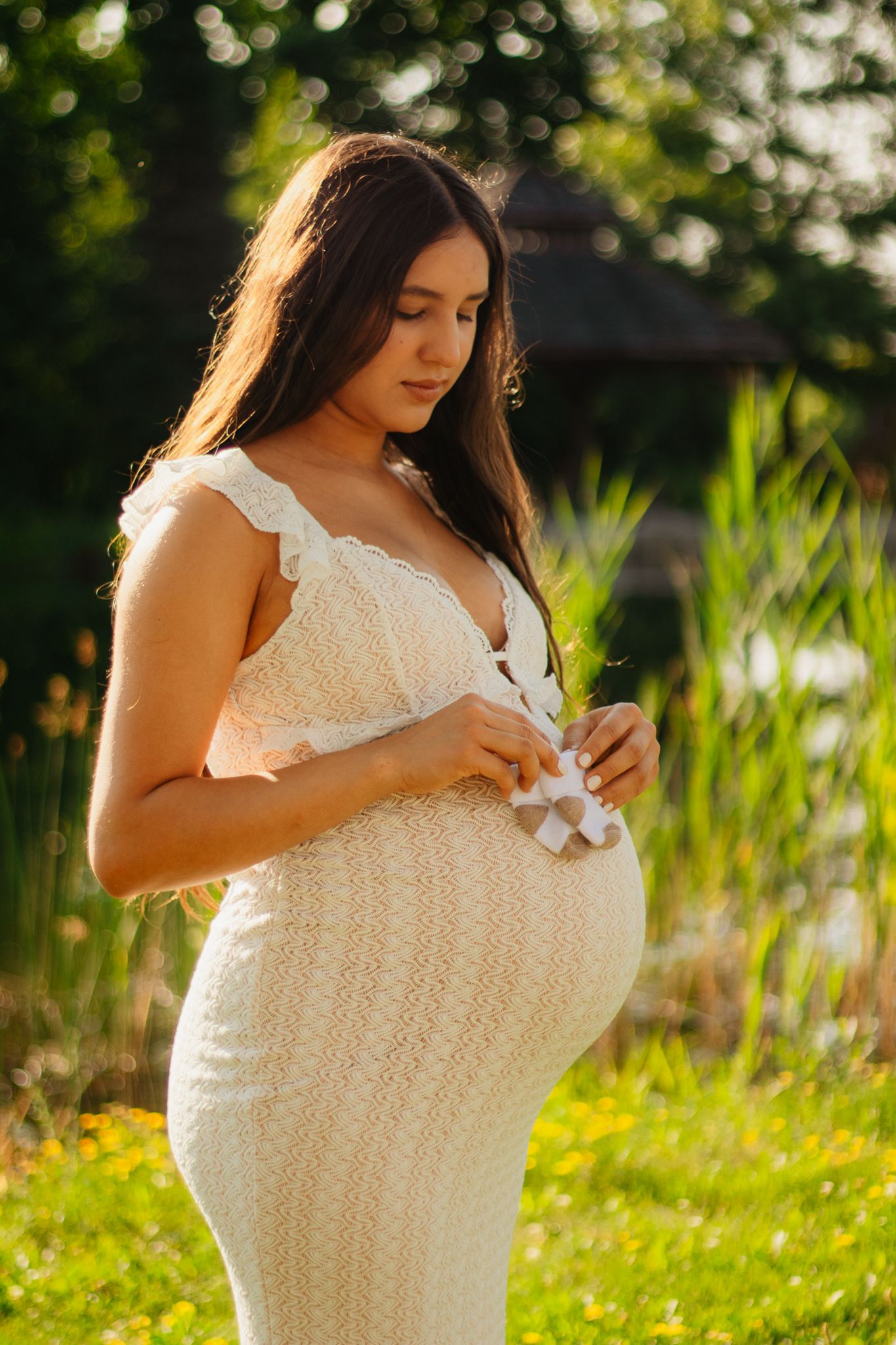 Side view of pregnant woman in lace dress during golden hour photoshoot.