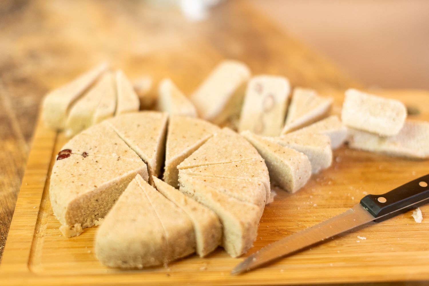 Close-up of traditional bread or bannock being sliced on wooden cutting board.