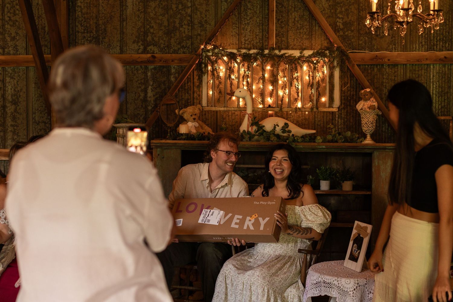 Dimly lit event space with vintage chandeliers and table settings.