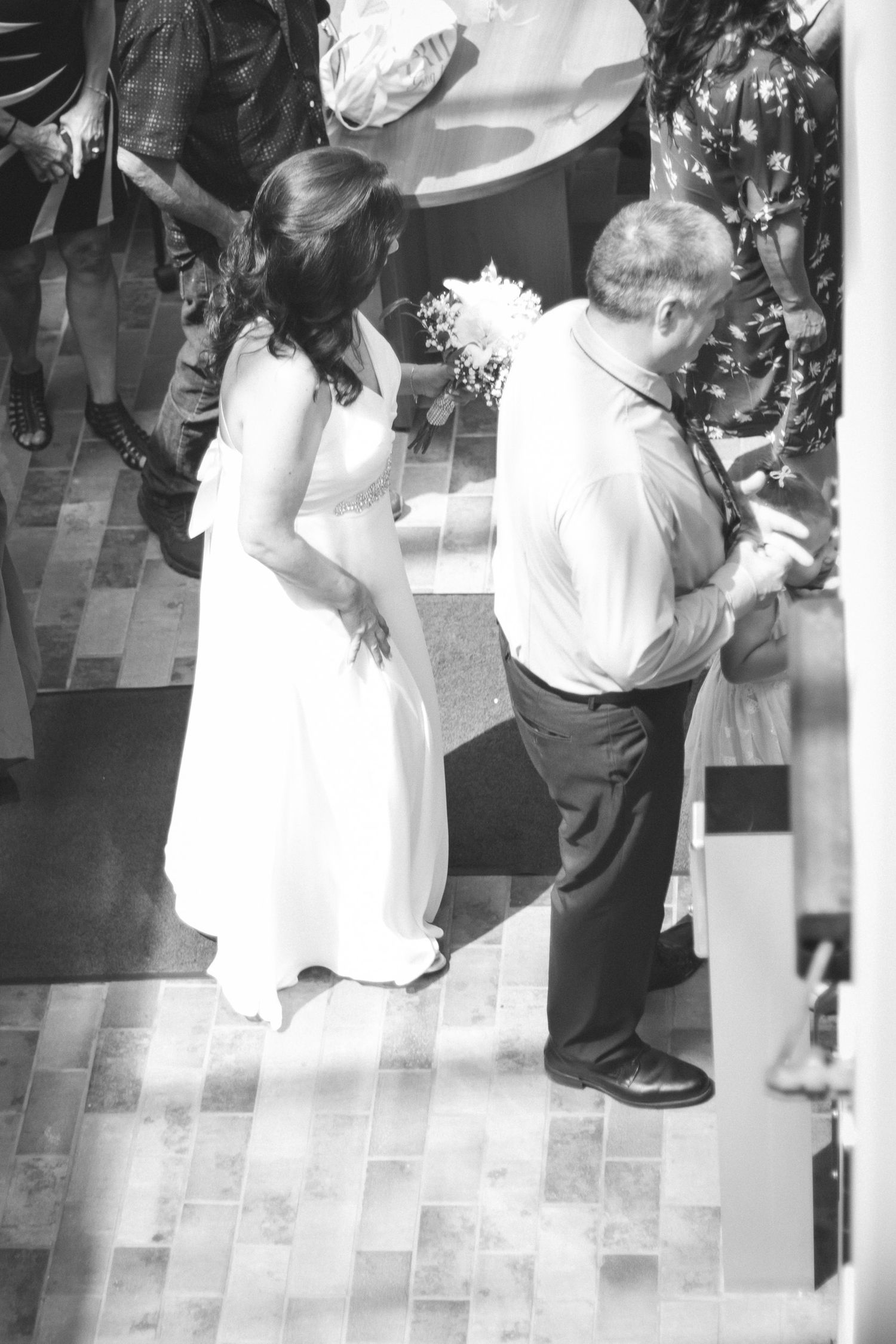 Black and white aerial view of bride in white gown and groom exchanging rings at wedding ceremony.