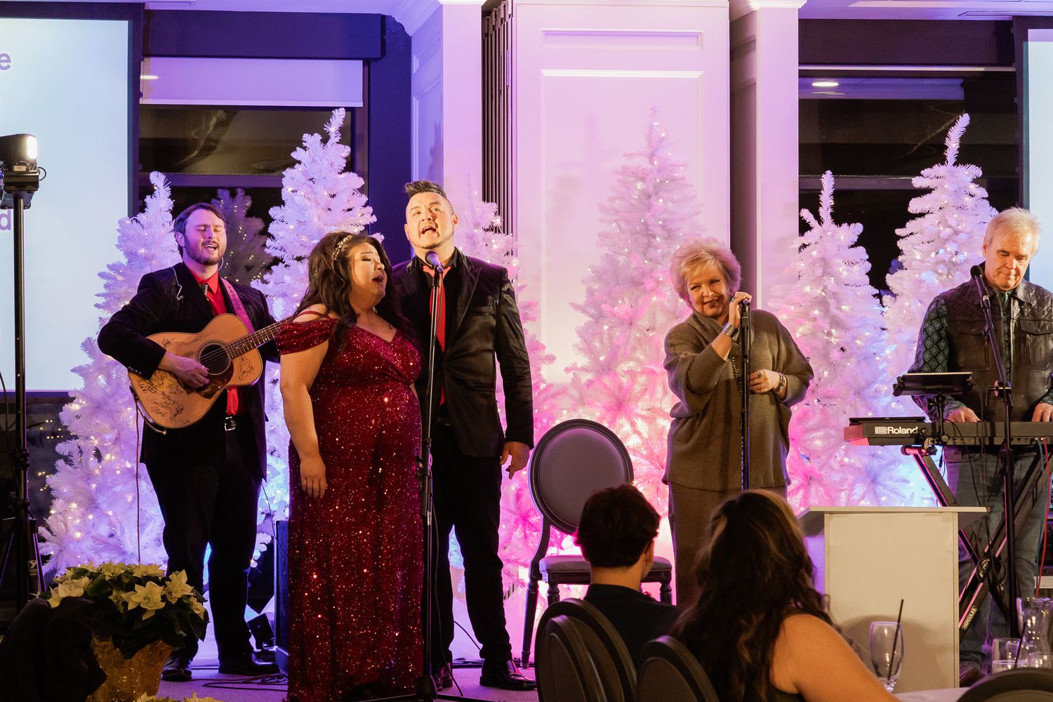 Live band performing at a holiday event with festive decorations and lighting.