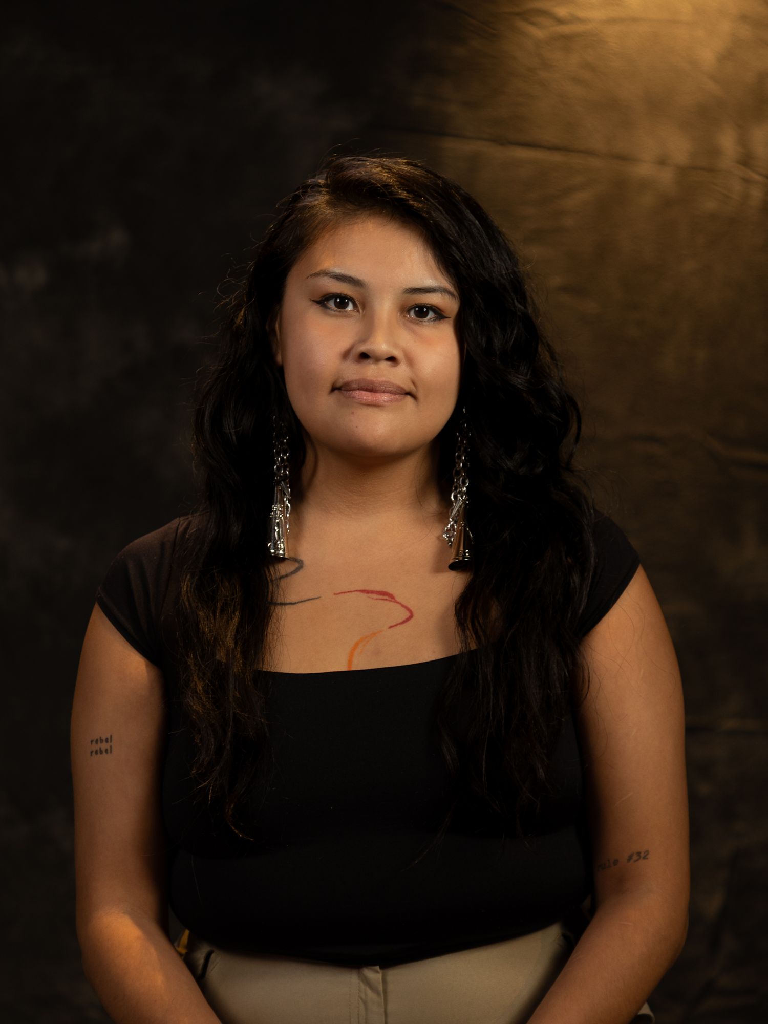 Professional studio portrait with dramatic lighting against a dark textured background.