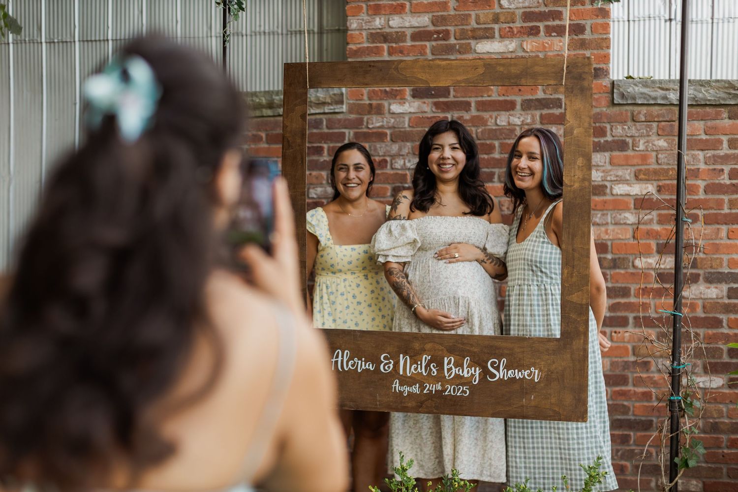 Baby shower celebration with brick wall backdrop and festive decorations.