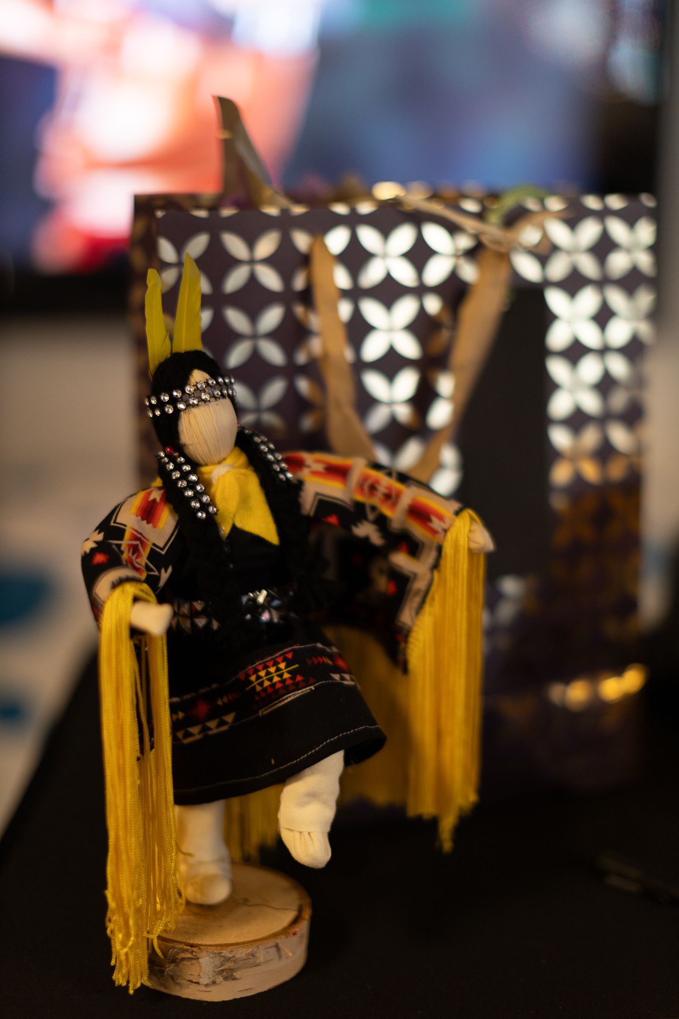 Decorative Native American kachina doll figure displayed against patterned background.