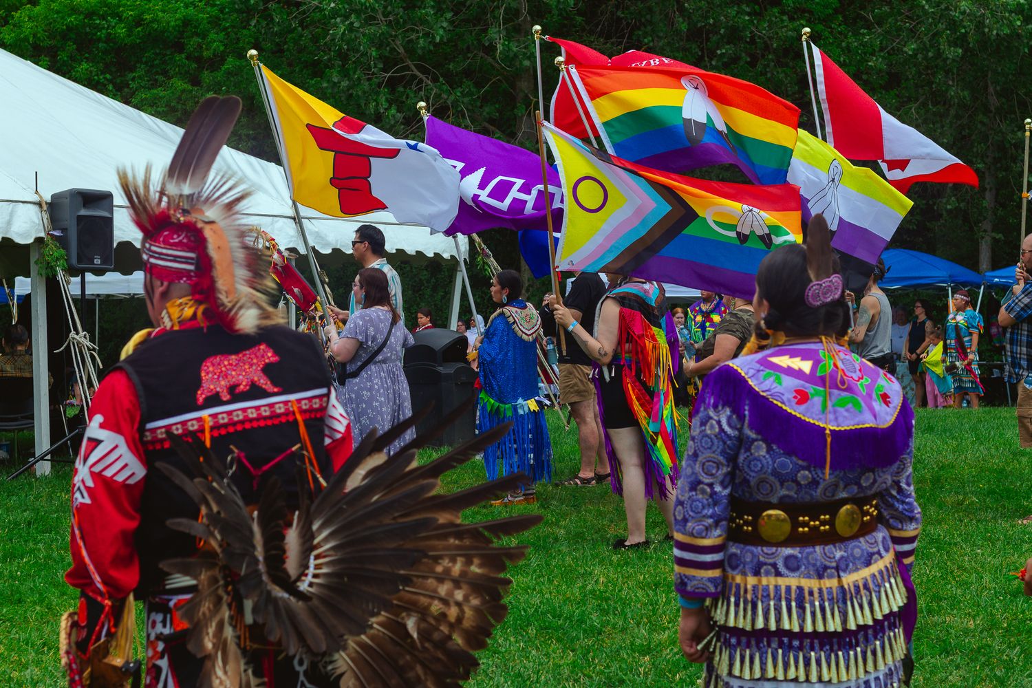Colorful flags and traditional dancers performing at an outdoor cultural festival.
