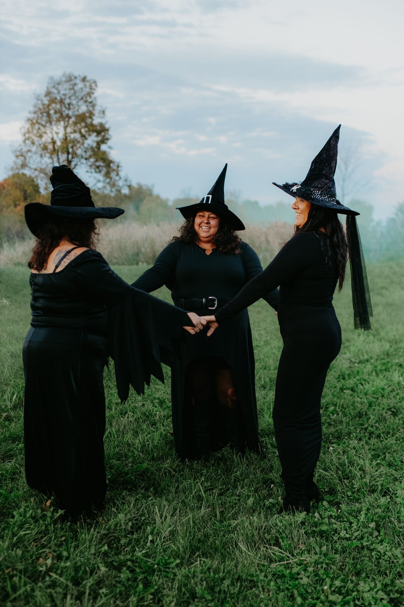 Group dressed as witches in black robes and hats playing in a green field.