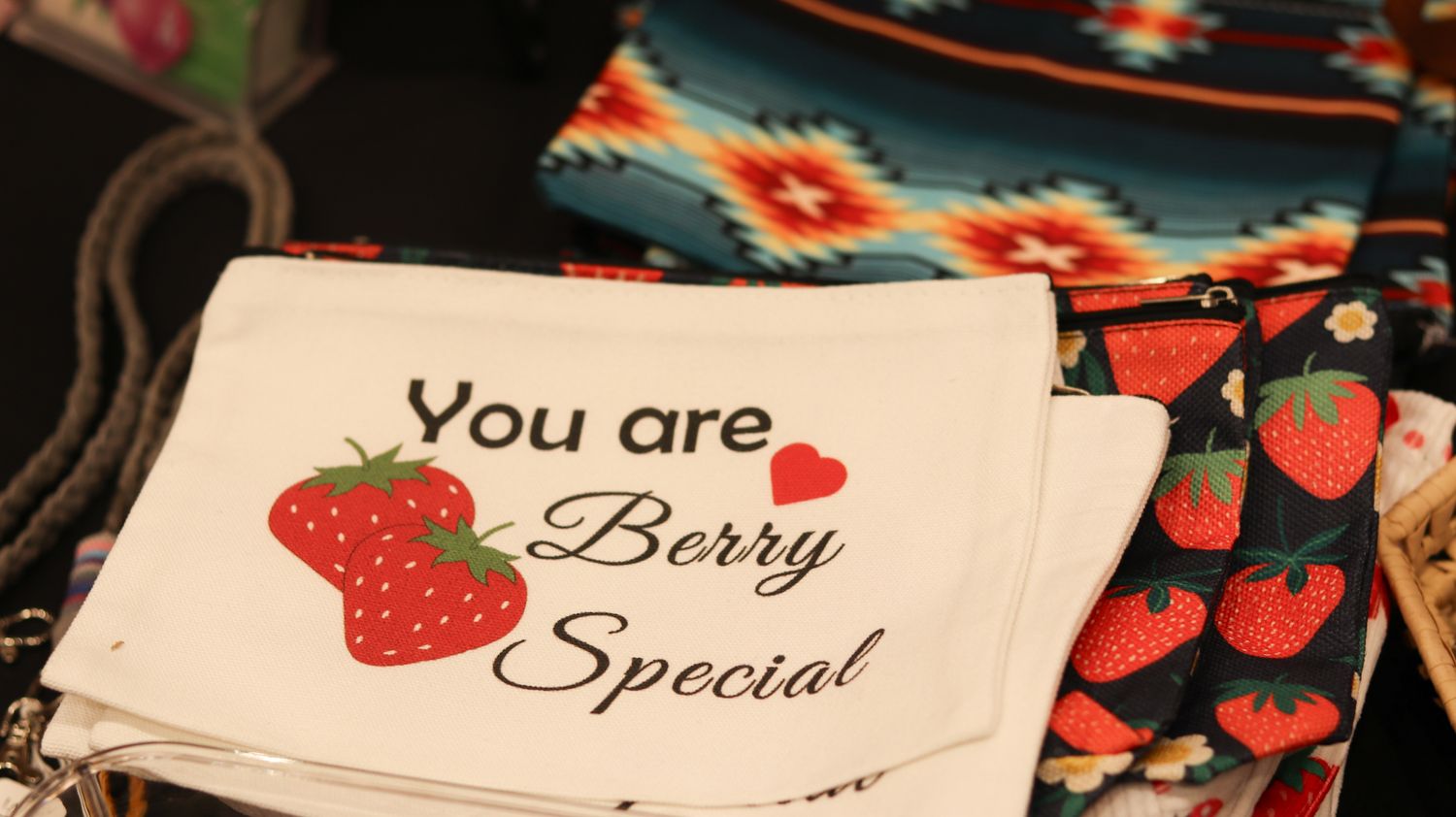 White gift tags reading You are Berry Special with strawberry graphics, displayed near colorful fabric at a market.
