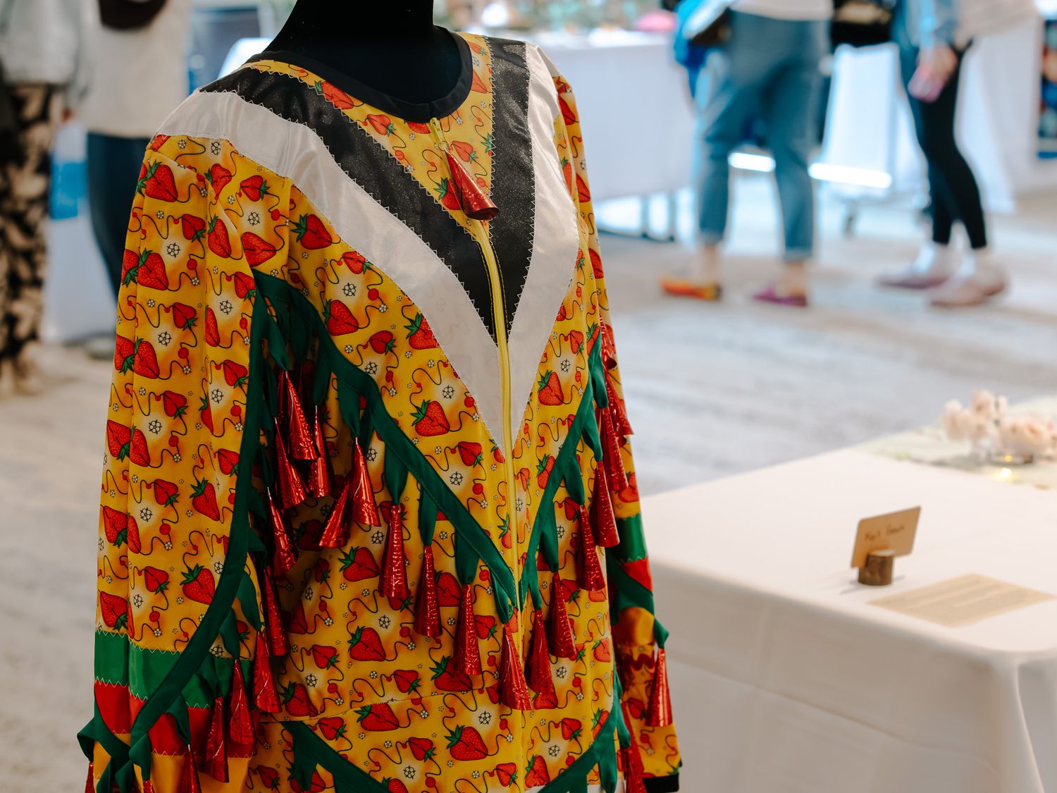 Colorful African print dress on mannequin displayed at an exhibition, featuring bold red, yellow, and green patterns.