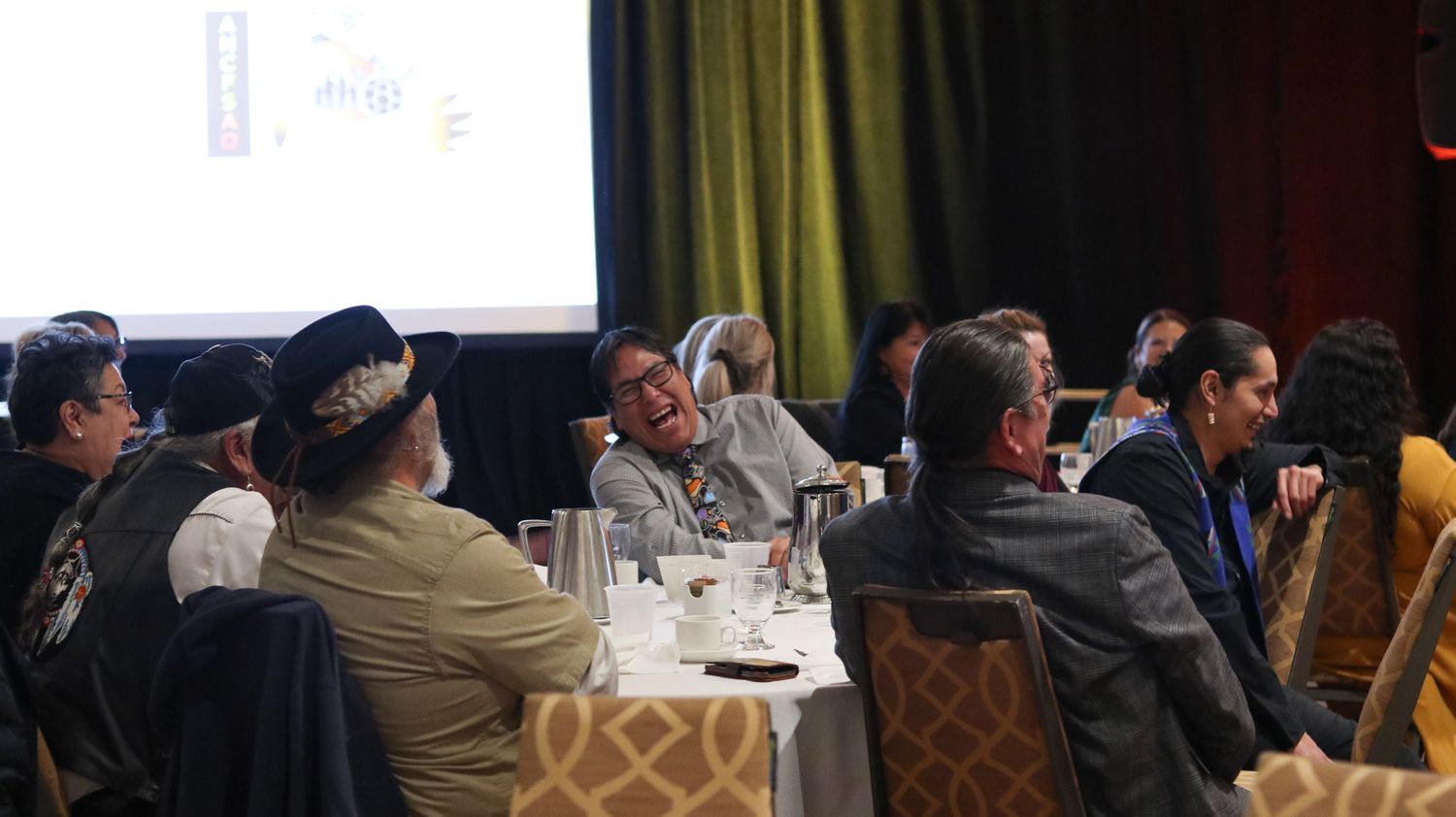 Diverse group of professionals networking and laughing at a conference dinner event.