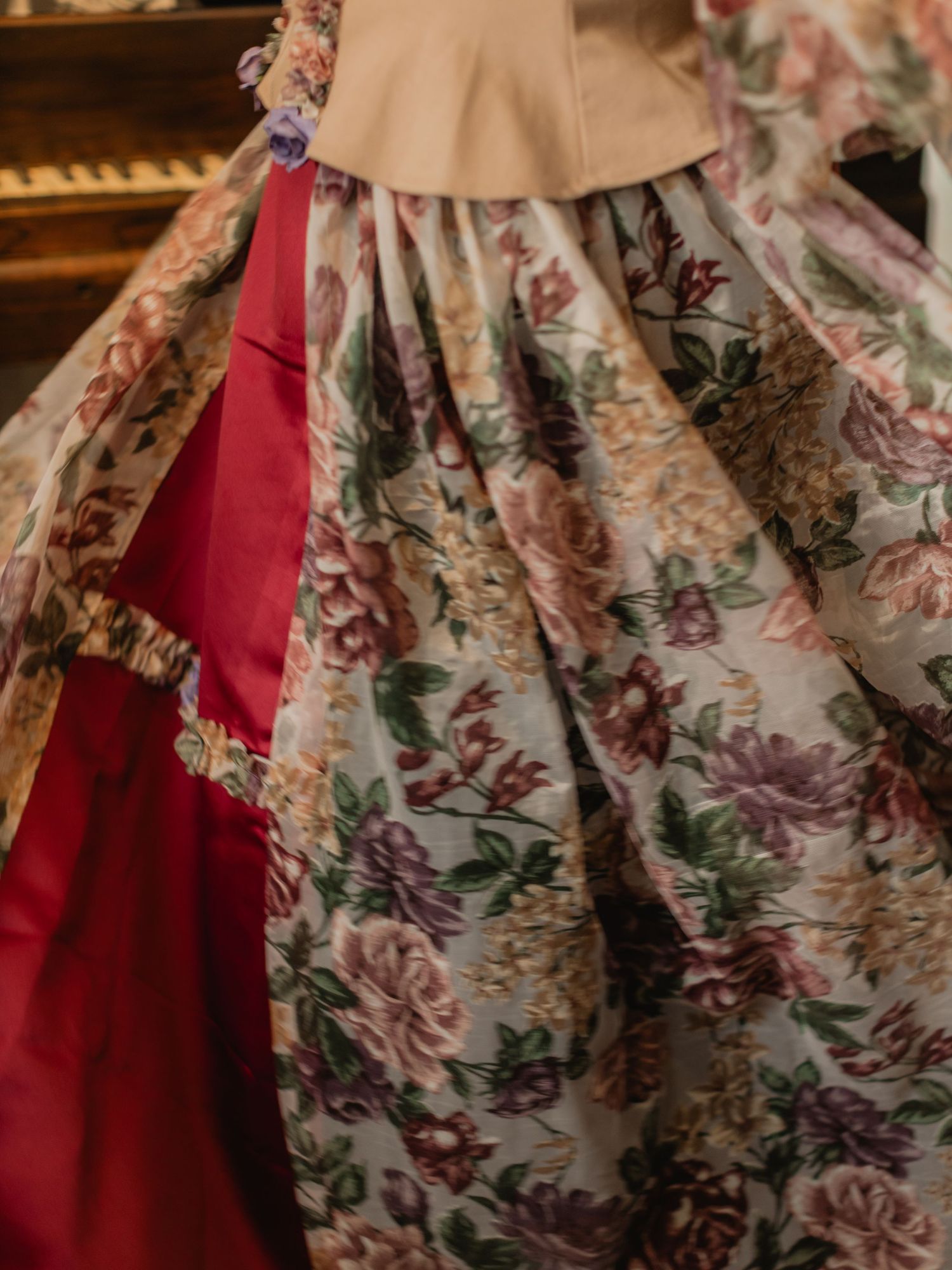 Elegant floral and red satin Victorian ballgown skirt with intricate pleating and floral fabric detail on display.