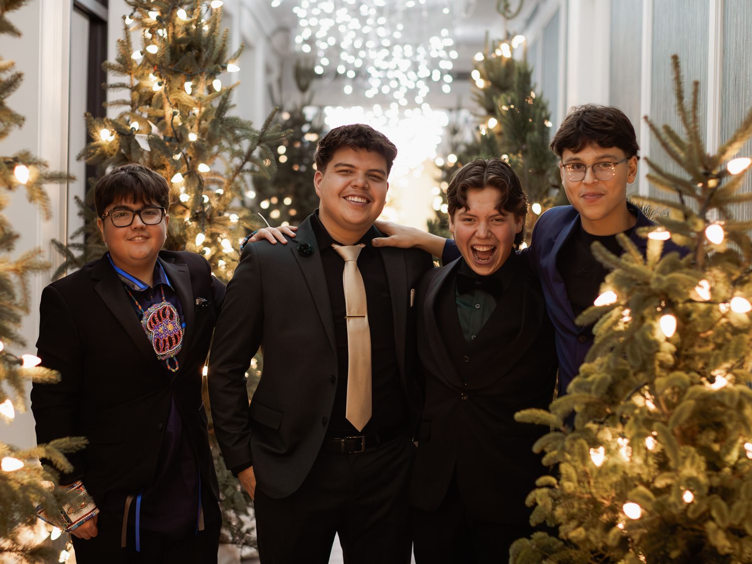 Group photo in front of illuminated Christmas trees and holiday decorations.