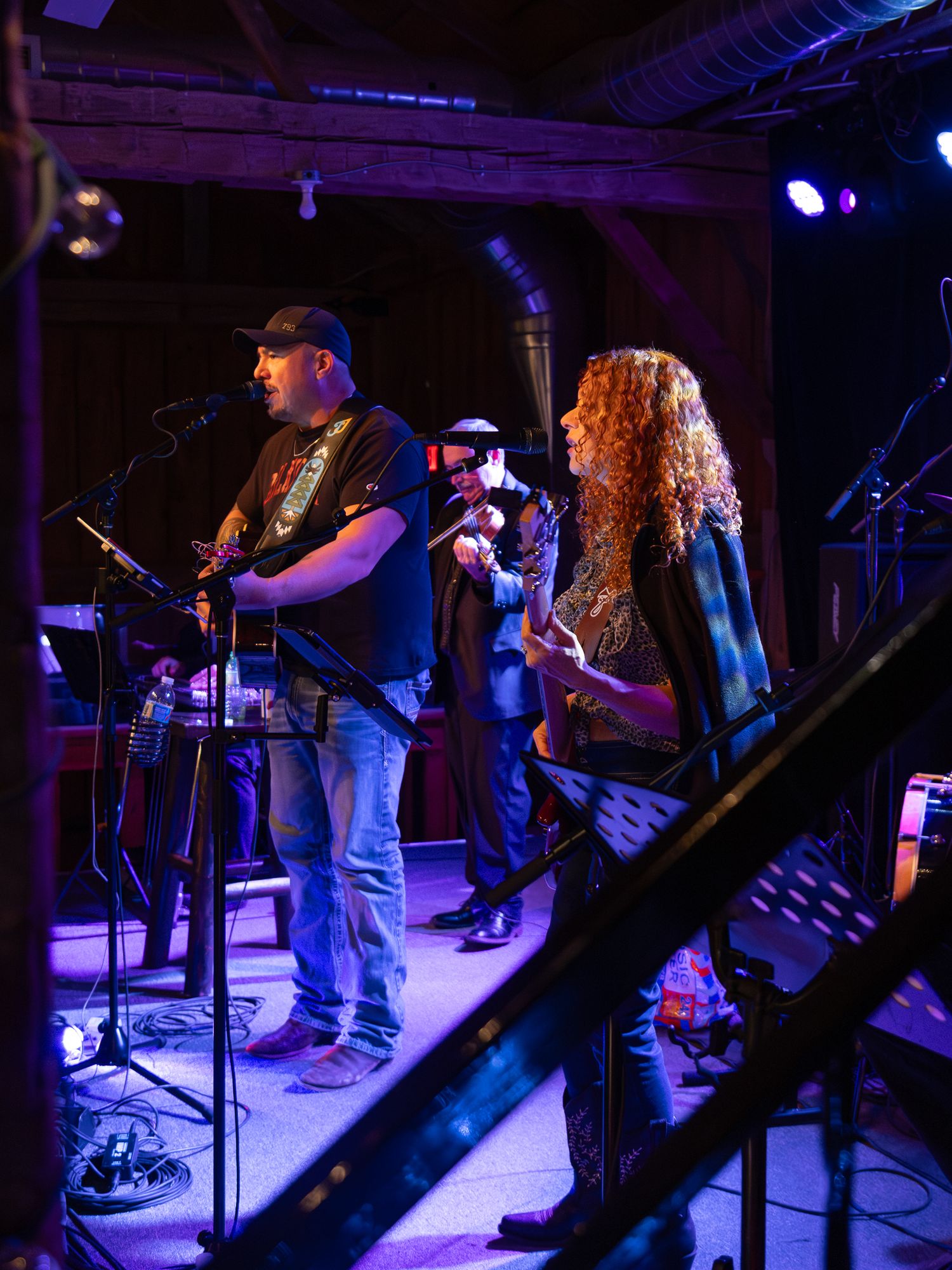 Musicians perform on a dimly lit stage with blue lighting effects.