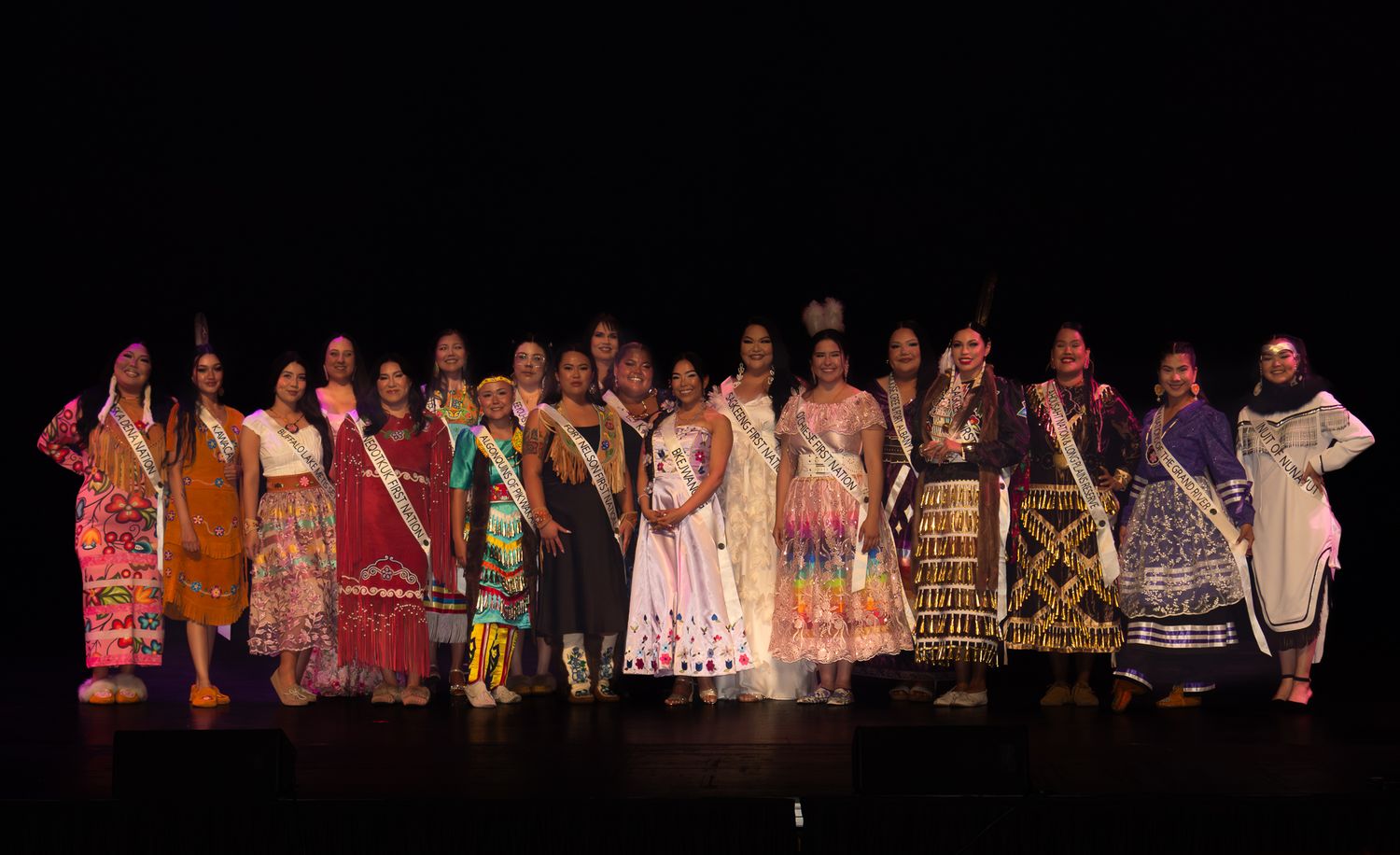 Stage performance with multiple performers in traditional costumes against dark background.