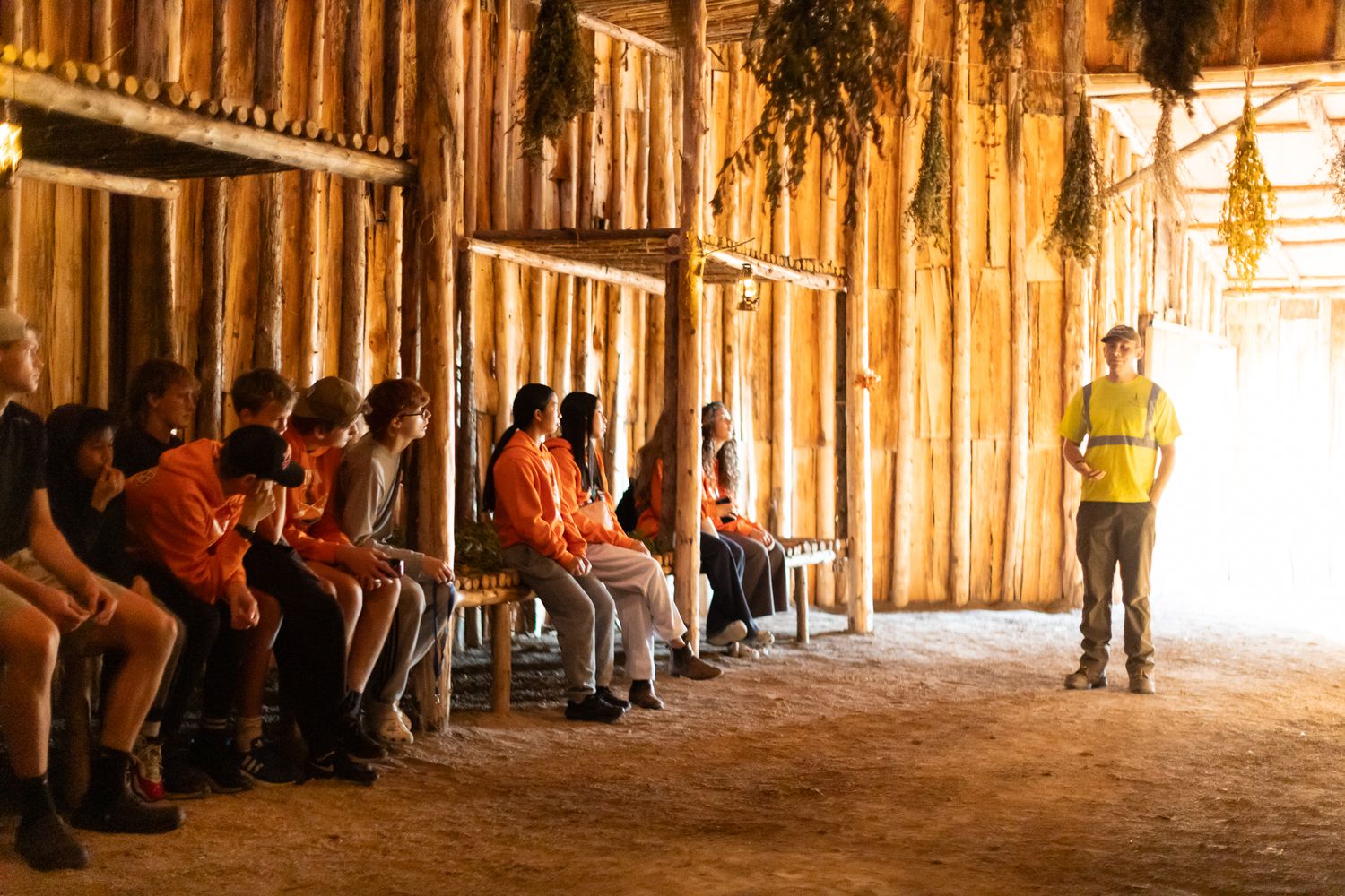 Interior of historic wooden longhouse with natural lighting streaming through.