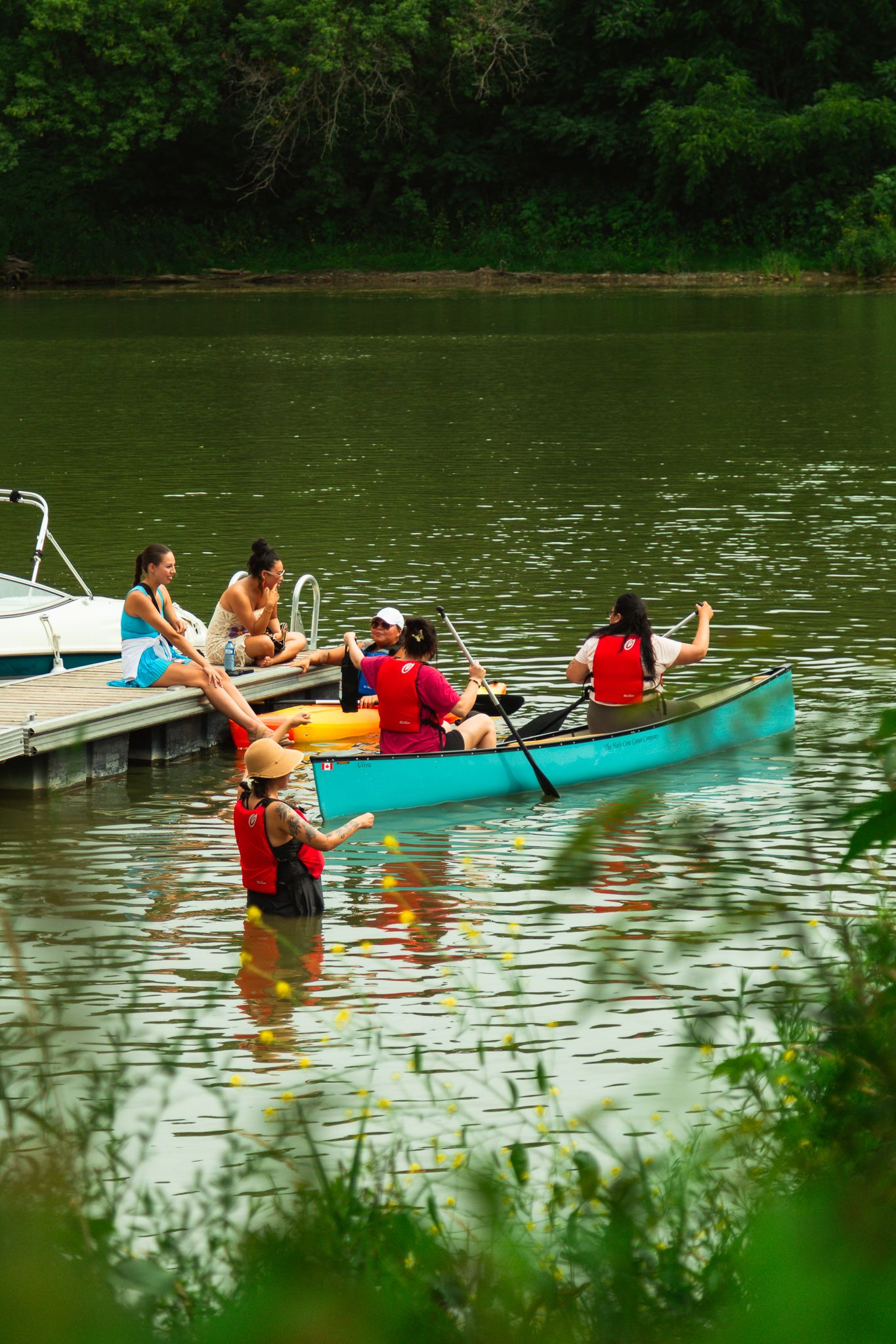 People enjoying kayaking and canoeing activities on a peaceful green lake.