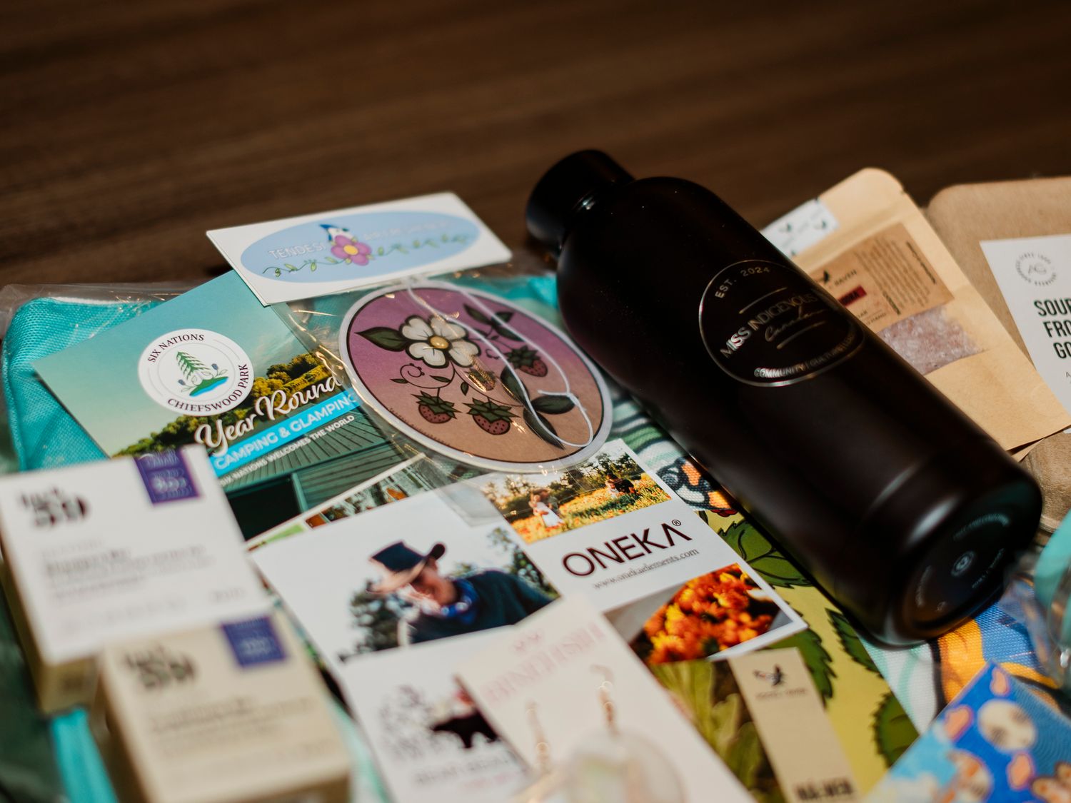 Flat lay of eco-friendly products including an Oneka bottle, stickers, and sustainable brand brochures on a wooden surface.
