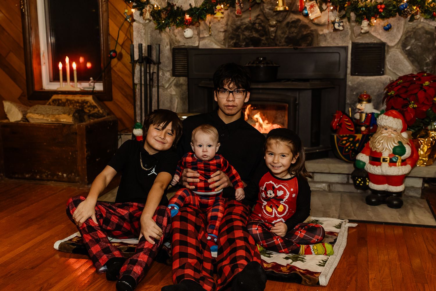 Cozy holiday scene with decorated Christmas tree, stockings, and family in coordinated red plaid outfits.