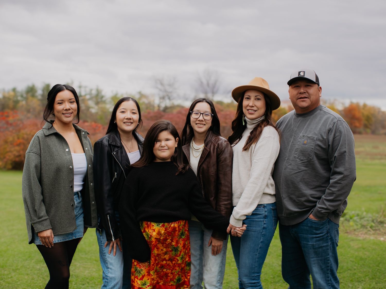 Group photo session in a field with fall foliage and a red barn in the background.