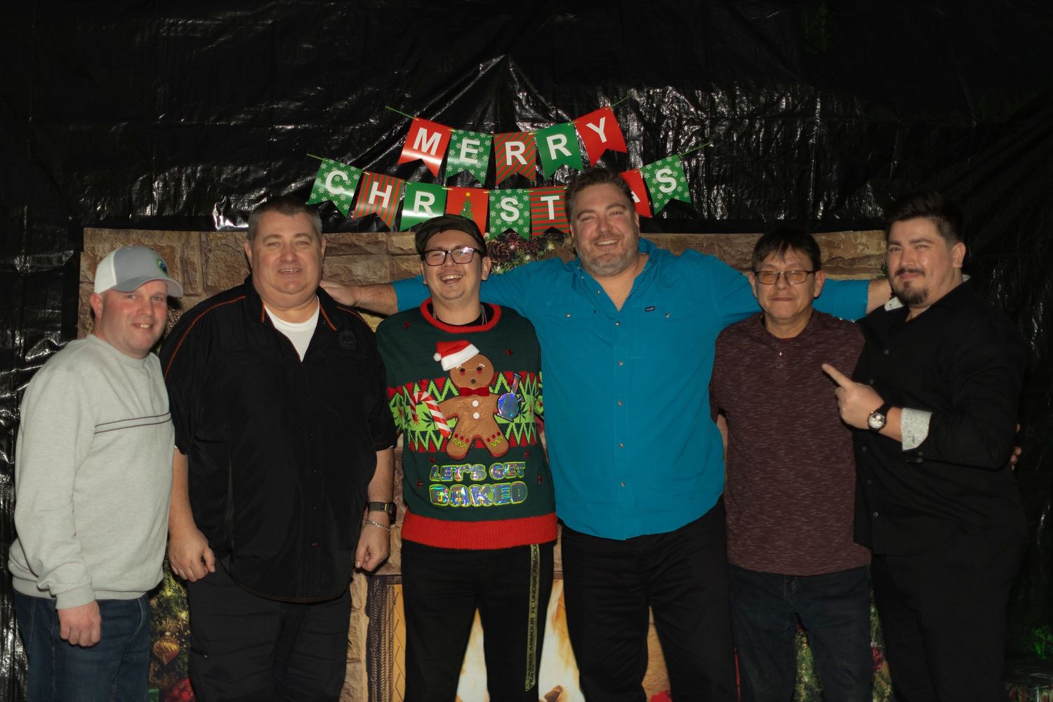 Group photo at a festive holiday gathering with Christmas decorations and lights.